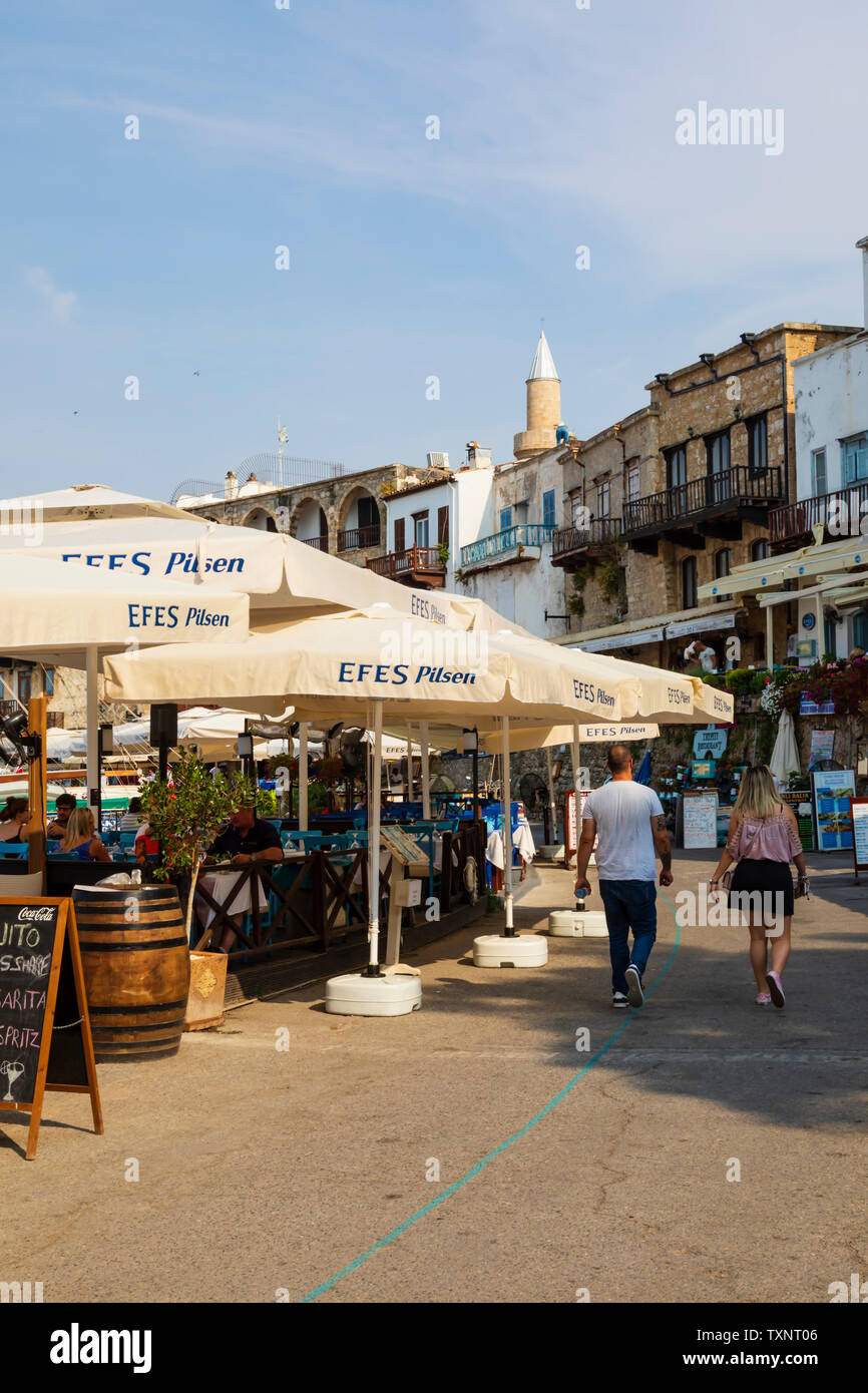 Touristen schlendern entlang der Hafenfront Restaurants, Kyrenia, Kas, Türkische Republik Nordzypern. Stockfoto