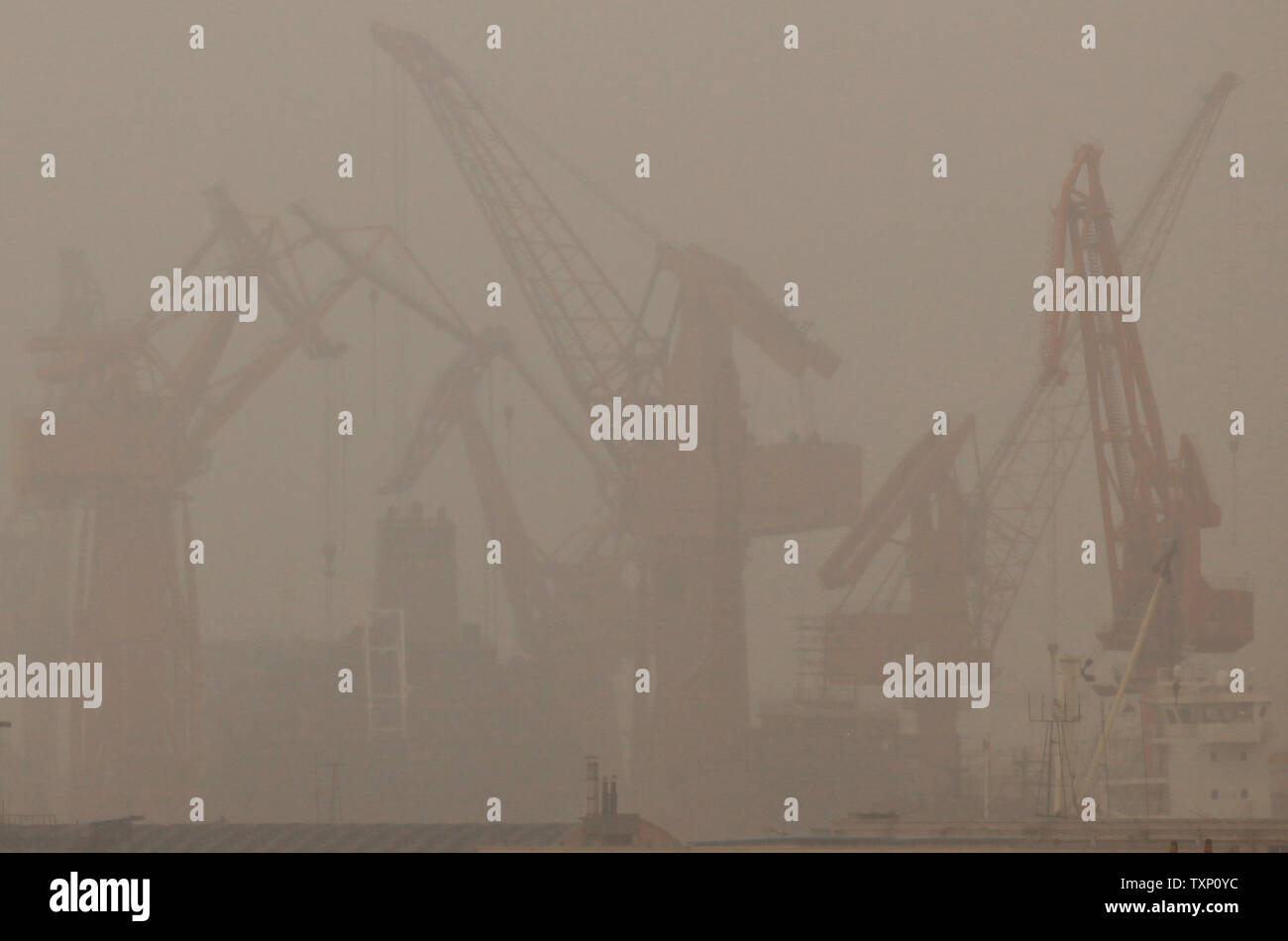 Alter chinesischer Containerbrücken ein riesiges Containerschiff entladen trotz der schweren Regenfälle im Nordosten Hafen des Landes Stadt Dalian am 30. August 2011. Der Hafen von Dalian, der nördlichste eisfreie Hafen in China, auch der größte multi-port im Nordosten Chinas und ist die zweitgrößte Container transshipment Hub in Festland China. UPI/Stephen Rasierer Stockfoto