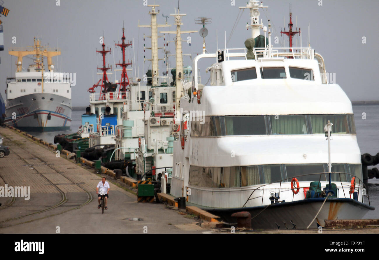Ein port Mitarbeiter Fahrräder Vergangenheit eine Reihe von Fähren und Schlepper im Nordosten Hafen des Landes Stadt Dalian am 29. August 2011 angedockt. Der Hafen von Dalian, der nördlichste eisfreie Hafen in China, auch der größte multi-port im Nordosten Chinas und ist die zweitgrößte Container transshipment Hub in Festland China. UPI/Stephen Rasierer Stockfoto