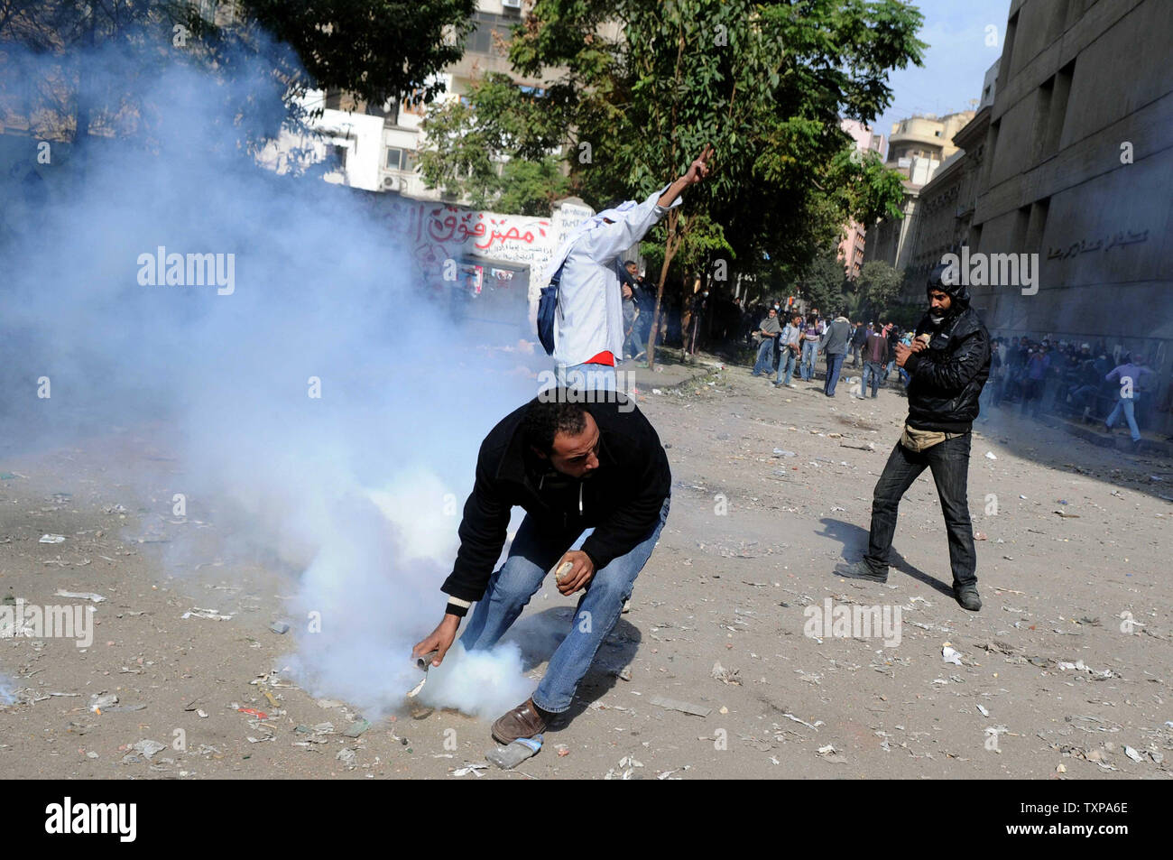 Eine Demonstrantin wirft ein Gas Kanister zur ägyptischen Polizisten, nicht gesehen, bei Auseinandersetzungen zwischen Polizei und Demonstranten in Kairo, Ägypten, Sonntag, November 20, 2011. Feuerte Tränengas und Gummigeschosse, ägyptische Polizei am Sonntag stießen für einen zweiten Tag mit Tausenden von Felsen werfende Demonstranten fordern, dass die herrschenden Militärs schnell ein Datum die Macht an eine gewählte Regierung zur Hand geben. UPI/Mohamed Hossam Stockfoto