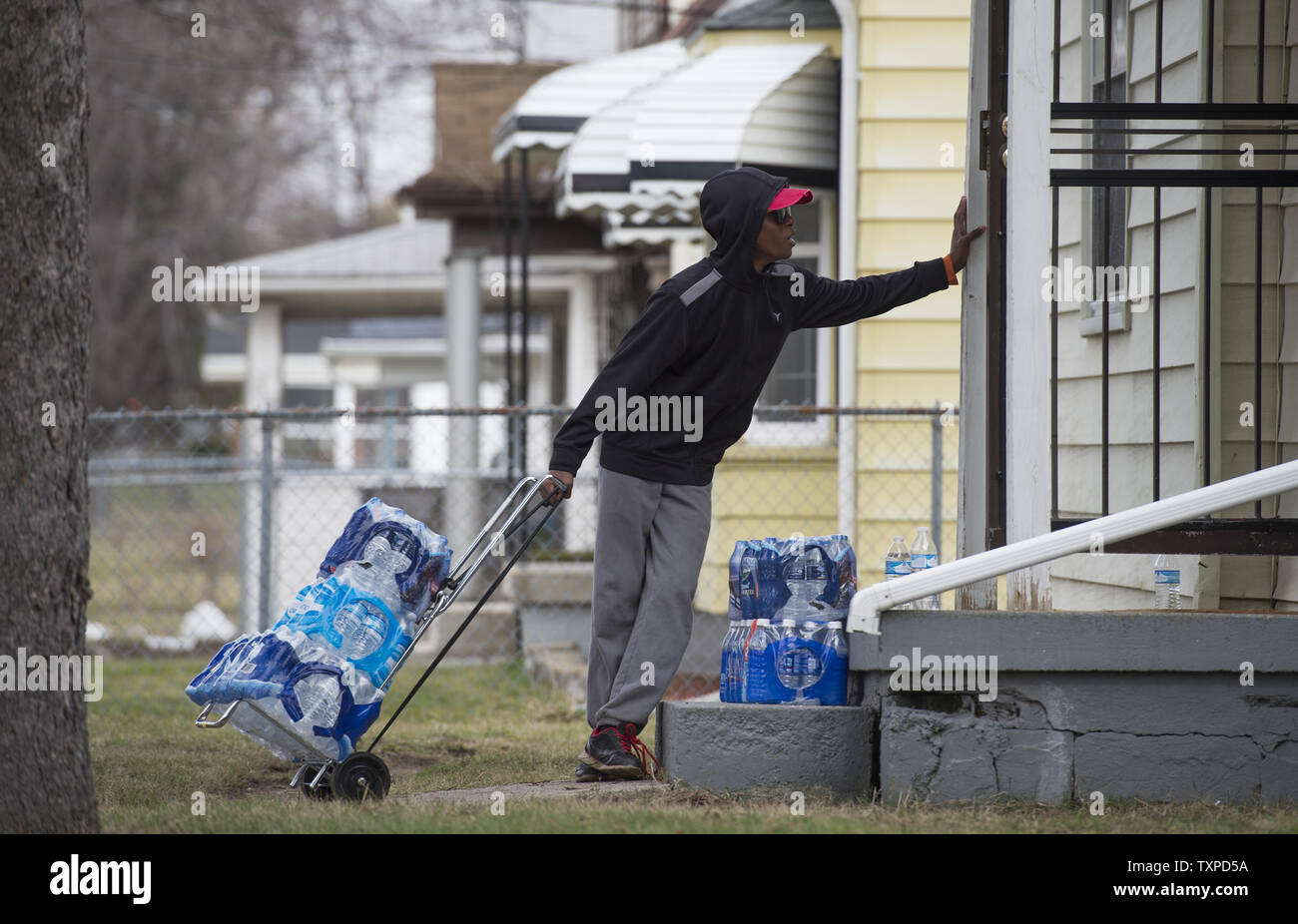Ein junger Mann Transporte Fälle von Wasser, um ein Haus in Flint, Michigan, 12. März 2016. Feuerstein Bewohner weiterhin Mineralwasser nach dem Trinkwasser zu verwenden, wurde gefunden, mit Blei verseucht zu sein, nachdem das Wasser Quelle aus Detroit Wasser und Kanalisation Abt. im April 2014 mit dem Flint River geschaltet war. Foto von Molly Riley/UPI Stockfoto