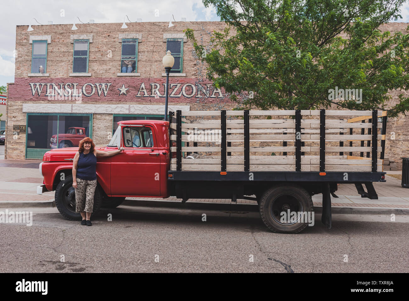 Winslow Arizona, USA 5/16/2016. Flatbed Ford mit Frau. Seite von Gebäude mit Kunst arbeiten, Windows, Menschen umarmen, Adler, Fahrzeug mit Fahrerin. Sig Stockfoto
