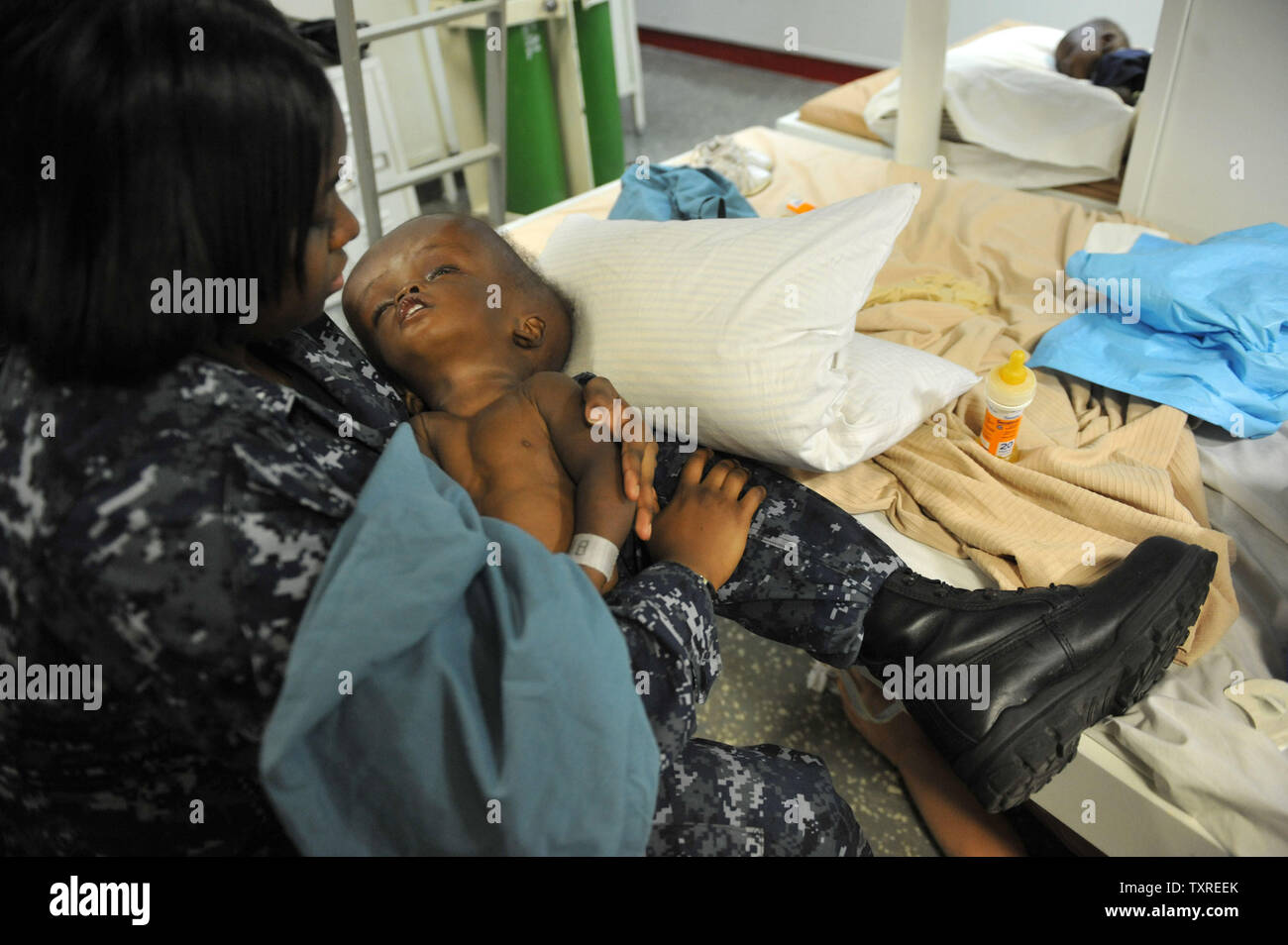 Eine junge Erdbeben Opfer wird durch eine Marine medizinische Mitarbeiter auf der USS Bataan gehalten, vor der Küste von Haiti, 20. Januar 2010. UPI/Kevin Dietsch.. Stockfoto Eine junge Erdbeben Opfer wird durch eine Marine medizinische Mitarbeiter auf der USS Bataan gehalten, vor der Küste von Haiti, 20. Januar 2010. UPI/Kevin Dietsch.. Stockfoto