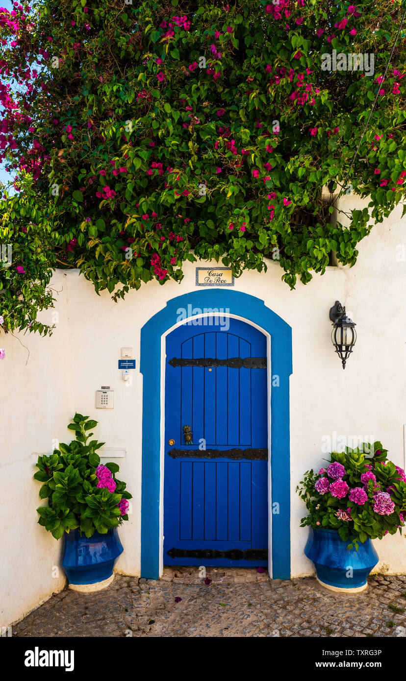 Auffällige blaue Tür mit lila Blumen umgeben, Portugal Stockfoto