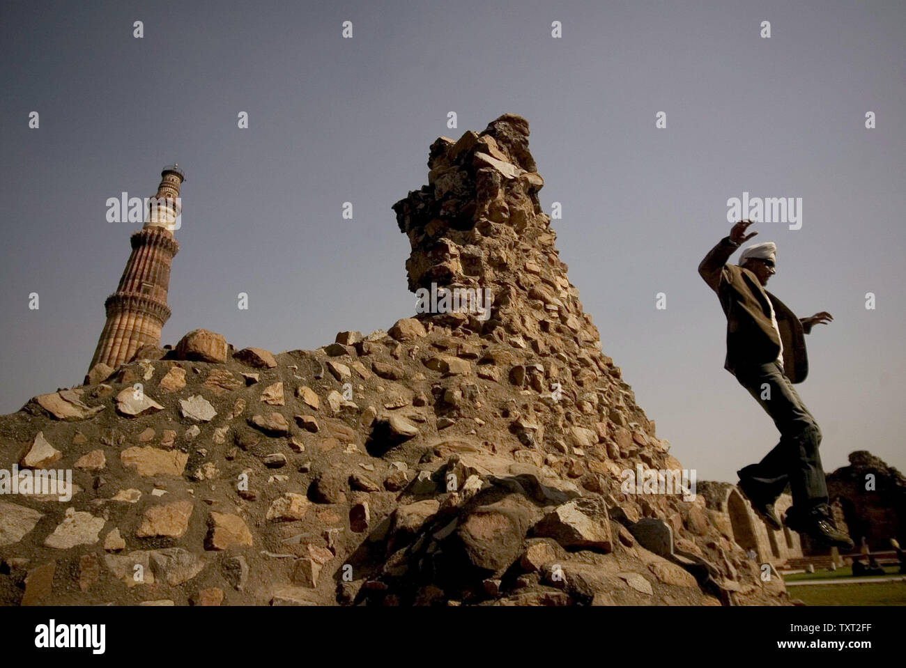 Einen indischen Mann springt aus einem Hügel vor der weltweit höchsten gemauerten Minarett Qutb Minar (L), wo der Bau in 1193, unter den Befehlen von Indiens erste muslimische Herrscher Qutb-ud-din Aibak in Neu Delhi, Indien Am 9. März 2009 gestartet. Das Qutb Minar ist 72 Meter hoch (237.8 ft) mit 379 Stufen nach oben. (UPI Foto/Mohammad Kheirkhah) Stockfoto