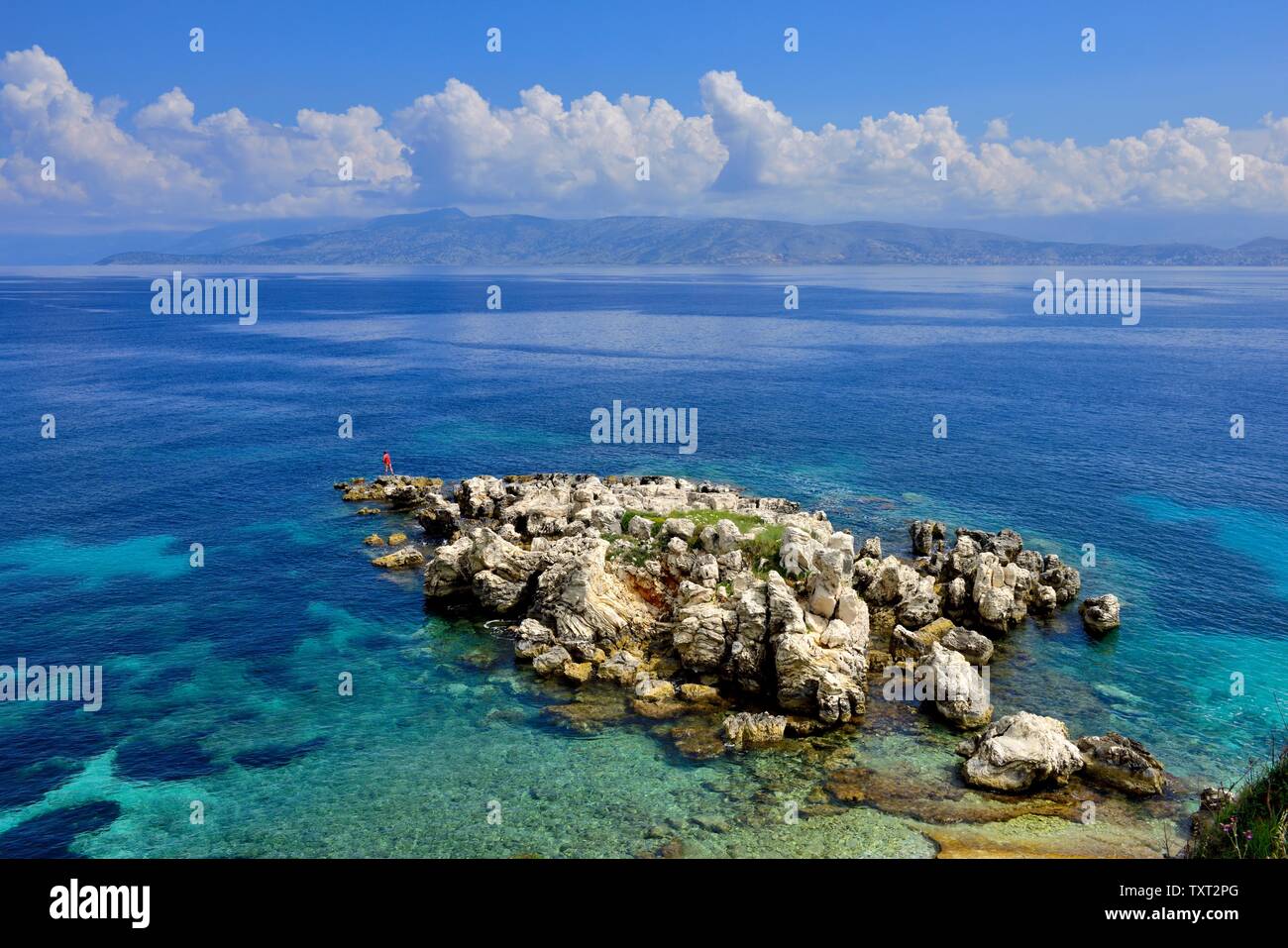 Ein Mann angeln von einigen Felsen in Kassiopi, Kassopaia, Ionische Inseln, Korfu, Griechenland Stockfoto