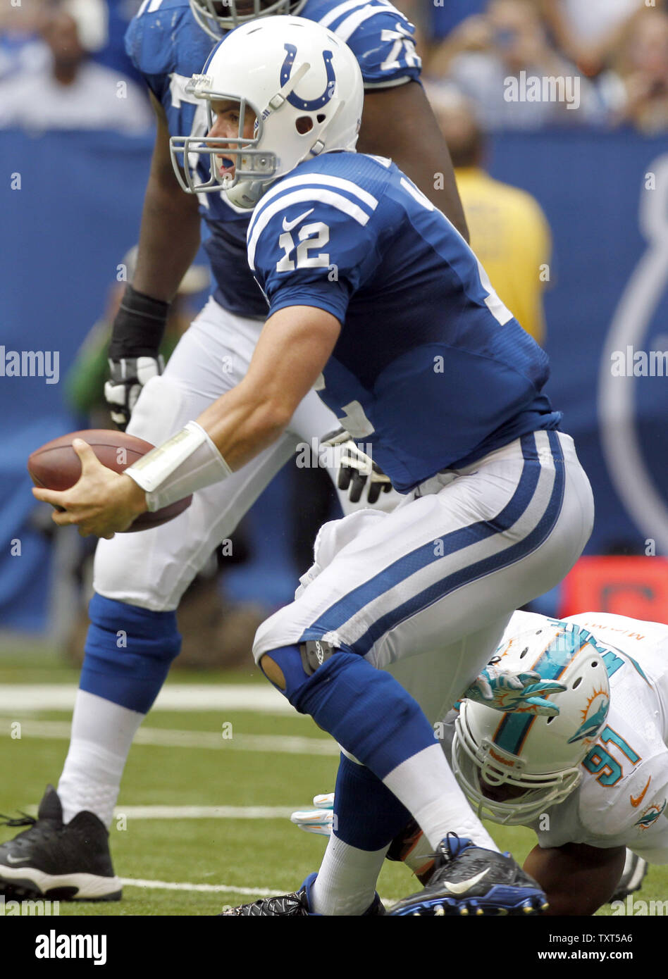 Indianapolis Colts quarterback Andreas Luck (12) kriecht Miami Dolphins defensive Ende Cameron Wake (91) im vierten Quartal von Lucas Oil Field in Indianapolis, Indiana, am 15. September 2013 zu entkommen. Die Delphine besiegten die Colts 24-20. UPI/Mark Cowan Stockfoto