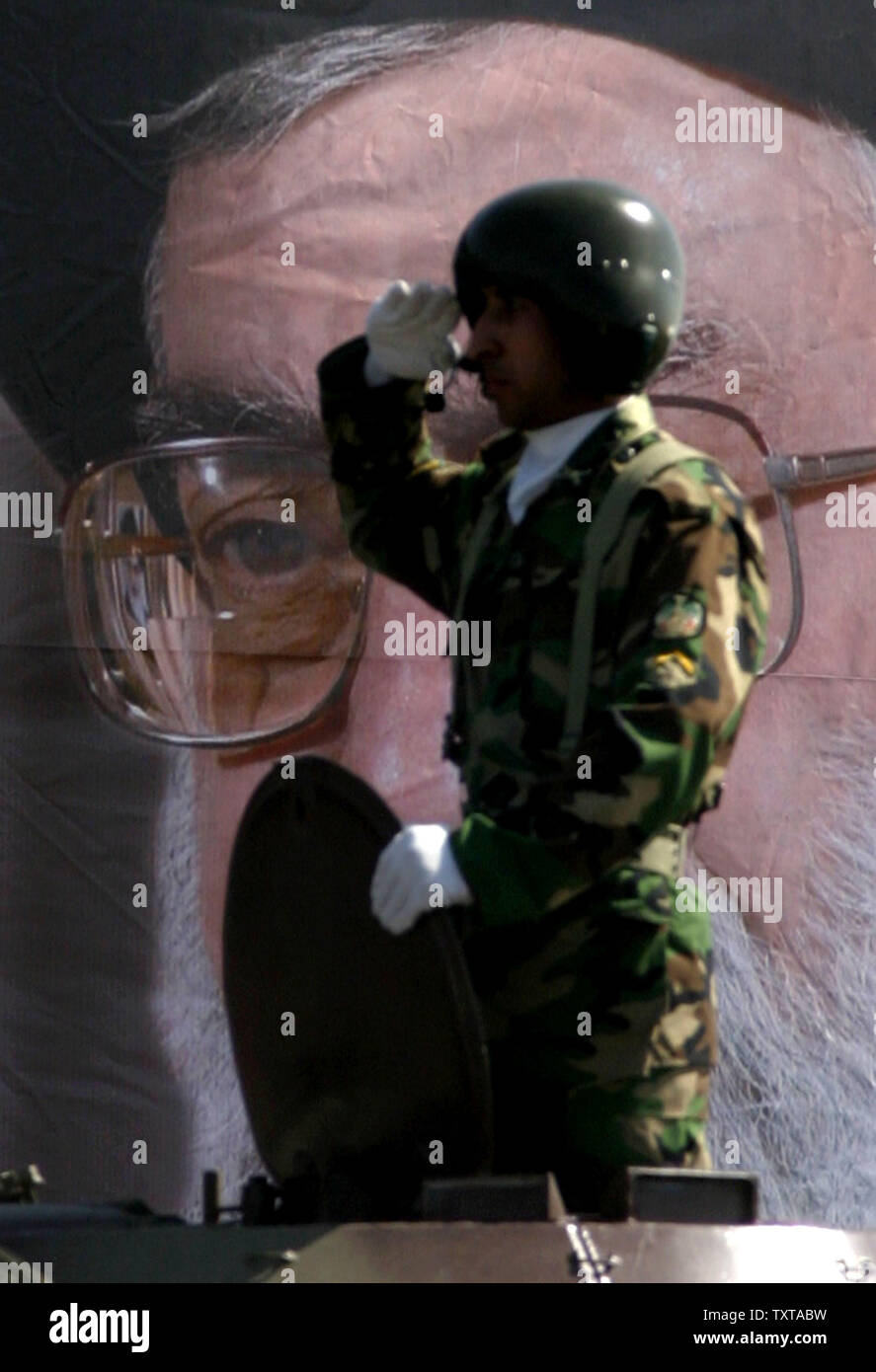 Ein Iranischer Soldat begrüßt vor einem Bild der Oberste Führer ...