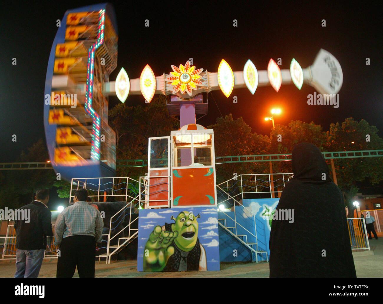 Iraner betrachten einen Carnival ride dekoriert mit einem Bild von Shrek amerikanischen Shrek (C) in Mellat Park in der Provinz Qazvin gesehen wird, 91 Meilen (165 km) westlich von Teheran, Iran am 21. Mai 2008. Die iranische Justiz offizielle warnte vor der "estructive' sozial-kulturellen Folgen der Barbie Puppen und anderen westlichen Spielzeug. Generalstaatsanwalt Ghorban Ali Dori Najafabadi sagte in einem offiziellen Schreiben an Vizepräsident Parviz Davoudi, dass die Puppe und andere westliche Spielwaren sind ein 'Gefahr', dass muss gestoppt werden, USA heute berichtet. (UPI Foto/Mohammad Kheirkhah) Stockfoto