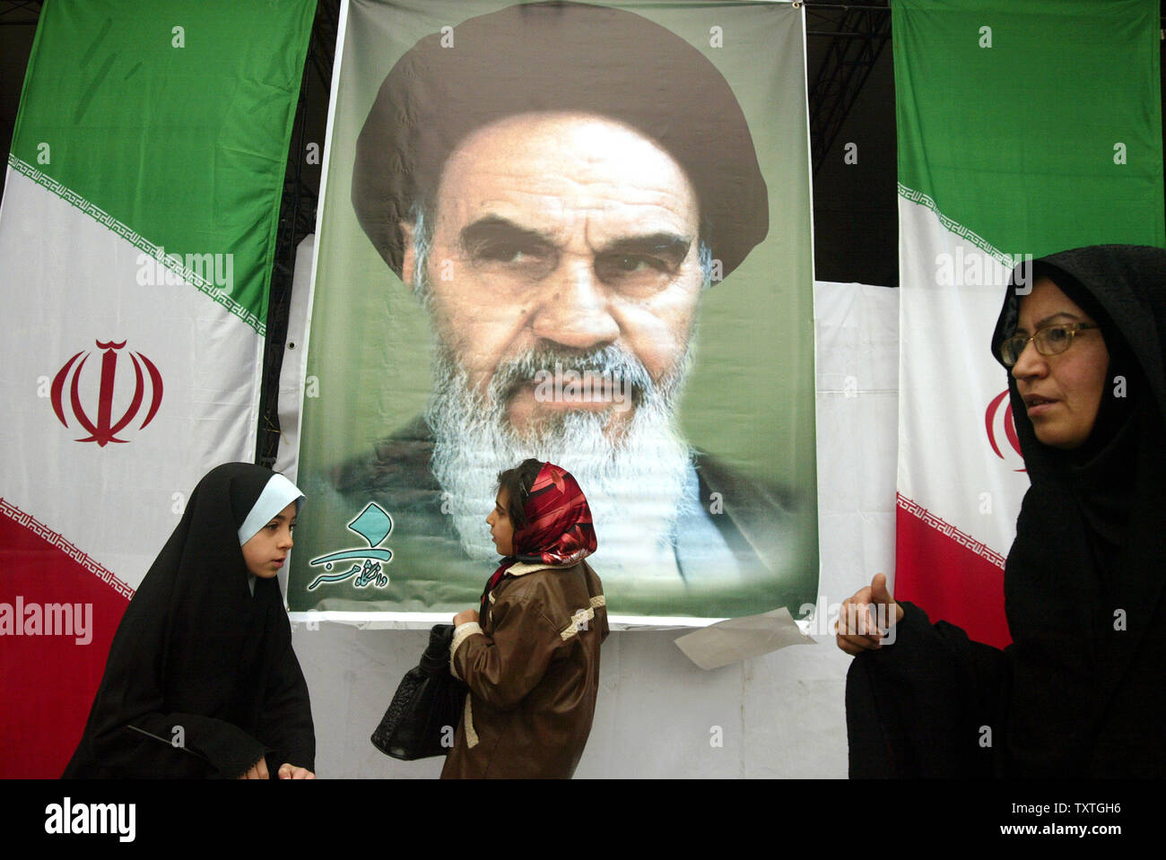 Iranische Frauen pass ein Bild von Iran ist spät revolutionäre Gründer Ayatollah Ruhollah Khomeini, wie Sie eine Rallye markiert den 30. Jahrestag der Islamischen Revolution des Iran in dem Azadi (Freiheit) Platz in Teheran, Iran am 10. Februar 2009 teil. (UPI Foto/Mohammad Kheirkhah) Stockfoto