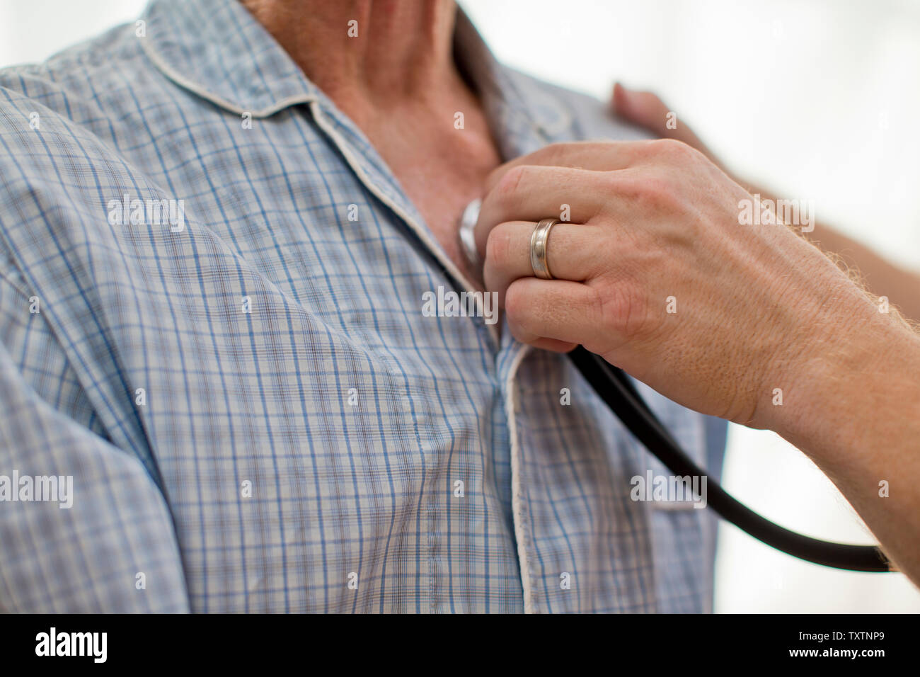 Von einem Krankenpfleger mit einem Stethoskop gegen die Brust ist ein älterer Mann. Stockfoto