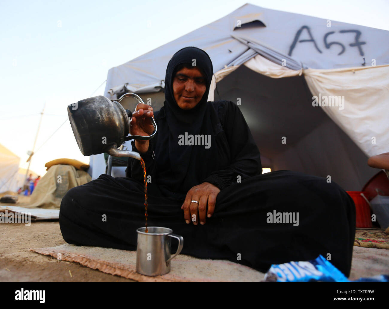 Irakischer Flüchtling Frau trinken Tee innerhalb des Khazer Flüchtlingslager am Stadtrand von Arbil, in der Irakischen Region Kurdistan, 20. Juni 2014. Zehntausende Menschen wurden in der irakischen Stadt Mossul geflohen, nachdem es von ISIS (Islamischer Staat im Irak und Syrien) Kämpfern überrannt wurde. Viele wurden vorübergehend an verschiedenen IDP-Camps rund um die Region, einschließlich des Bereichs in der Nähe von Erbil untergebracht, wie Sie die Sicherheit der in der Nähe der kurdischen Region zu geben Hoffnung. UPI/Ceerwan Aziz Stockfoto