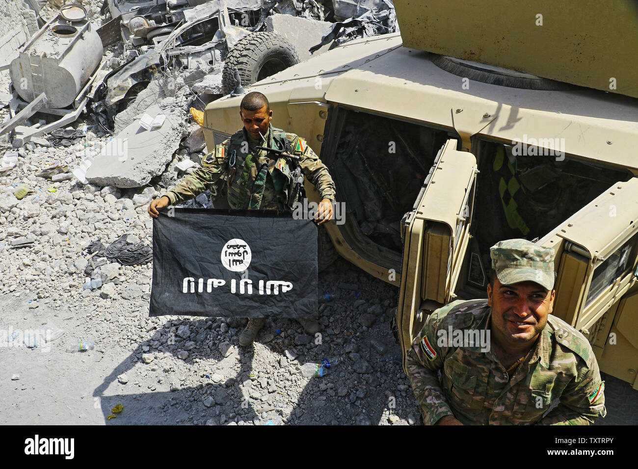 Eine irakische Kräfte Mitglied hält die Flagge von militanten islamischen Staat, wie er in der alten Stadt von Mosul, Irak am 10. Juli 2017 feiert. Irak verkündete einen endgültigen Sieg in den fast neun Monate offensive Mossul von Dschihadisten zu wiederholen, wie Feiern unter der Polizei in der Stadt brach. Foto von Hana Noori/UPI Stockfoto