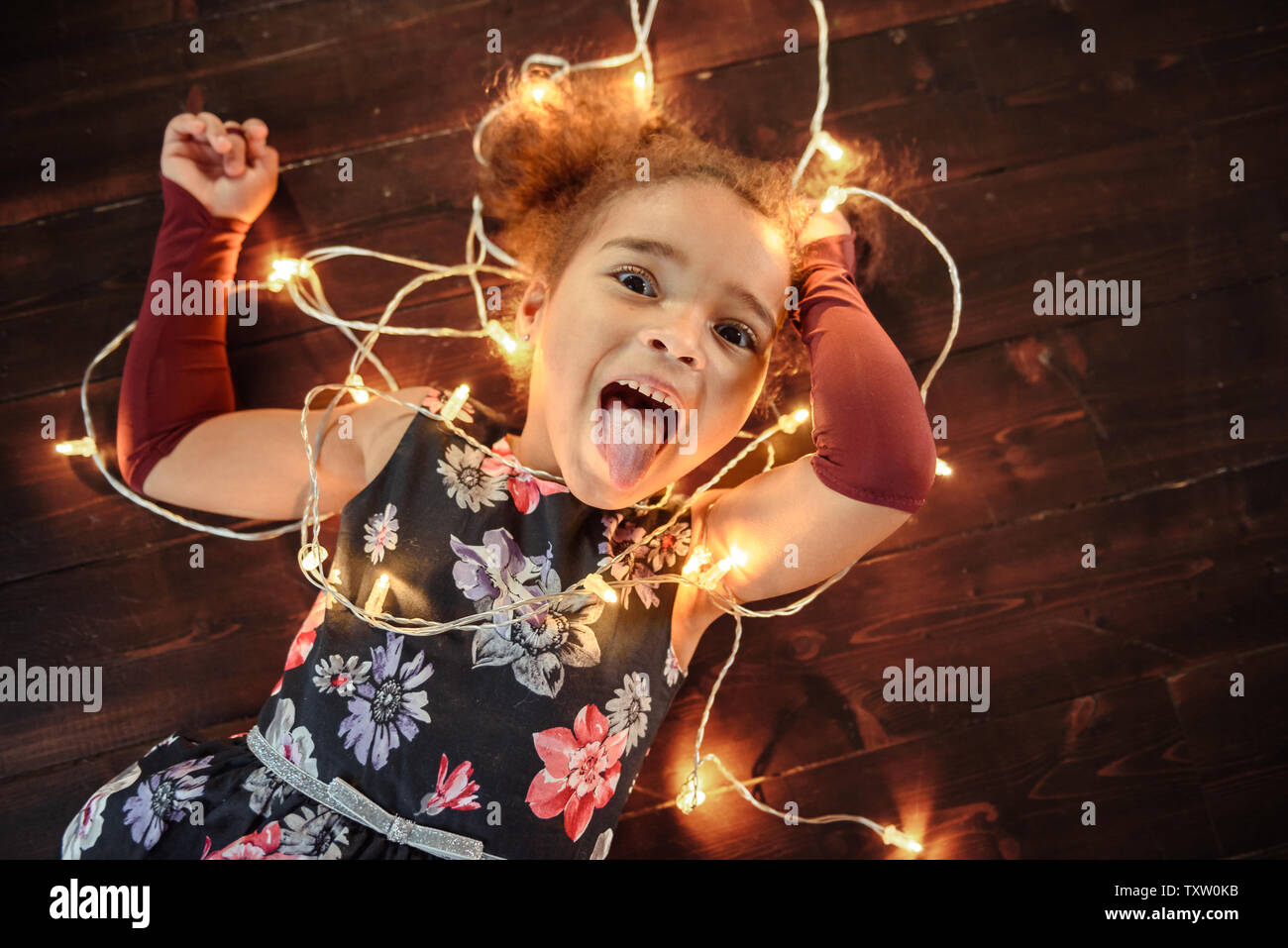 Süße kleine Mädchen mit auf Flor mit hellen christmas garland in ihrem Haar. Weihnachten Portrait, gemütlicher Stil. Ansicht von oben. Stockfoto