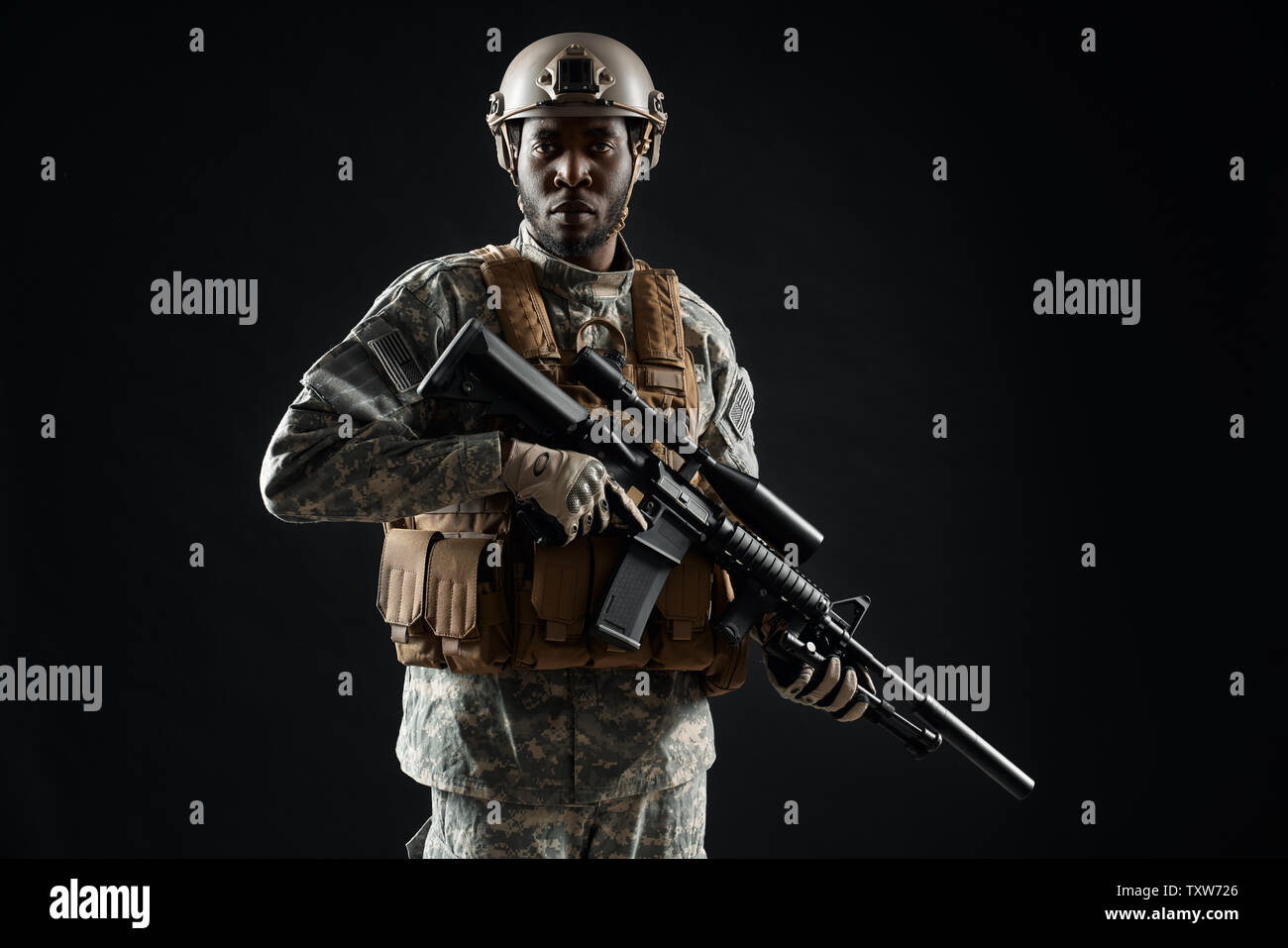 Vorderansicht der afrikanische Mann Soldat trägt Uniform Holding mit der Waffe in der Hand und überzeugt davon, Kamera schaut. Kutschen mann Vorbereitung für den Krieg. Konzept der Armee. Schwarzen Hintergrund. Stockfoto
