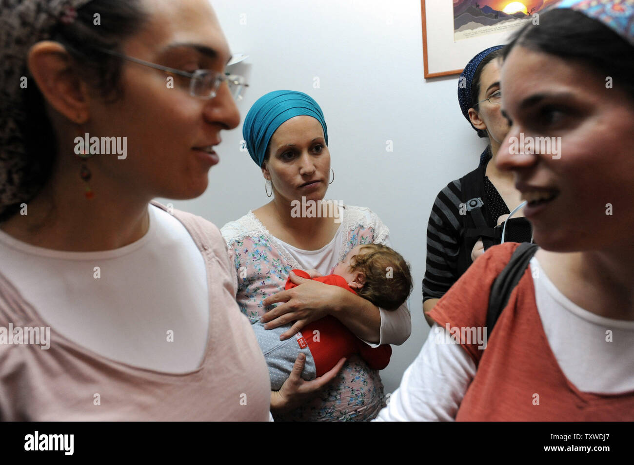 Ein israelischer Siedler hält Ihr Baby während einer Pressekonferenz über den Vertrag mit der israelischen Regierung für Siedler ihre Häuser freiwillig in der Ulpana Vorposten in der Nähe des Beit El Siedlungen in der West Bank, 28. Juni 2012 verlassen. Insgesamt 33 Familien verlassen ihre Wohnungen im Gegenzug für 300 neue Wohneinheiten im Beit El Siedlung gebaut werden. Die Evakuierung der fünf Gebäude in Ulpana wurde letzten Monat von der israelischen Obersten Gerichtshof bestellt, weil Sie auf Privaten palästinensischen Landes erbaut wurden. UPI/Debbie Hill Stockfoto