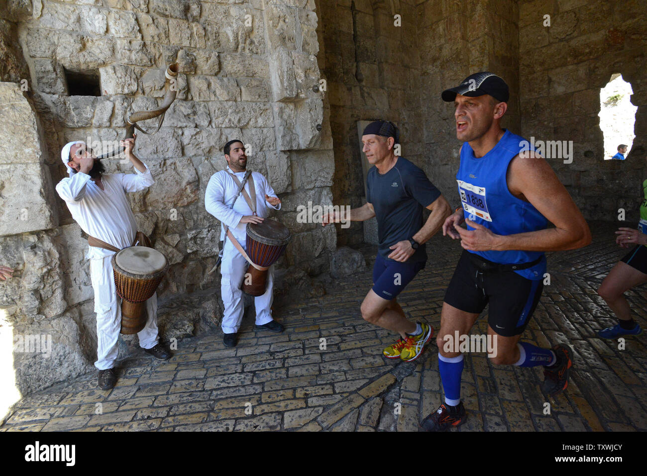 Lokale und internationale Läufer letzten israelischen Musikern innerhalb des Zion Gate in der Altstadt von Jerusalem während der vierten jährlichen Jerusalem Marathon in Jerusalem, Israel, 21. März 2014. Mehr als 25.000 Läuferinnen und Läufer aus 54 Ländern am Marathon teilgenommen. Kenia native Ronald Kimeli Kurgnt zuerst beendet, einen neuen Rekord von 2 Stunden, 16 Minuten, 9 Sekunden in die 26 Meile Rennen. UPI/Debbie Hügel. Stockfoto