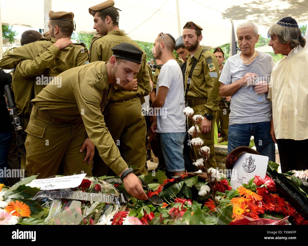Ein israelischer Löten legt einen Stein auf die Blumenbewachsenen Grab