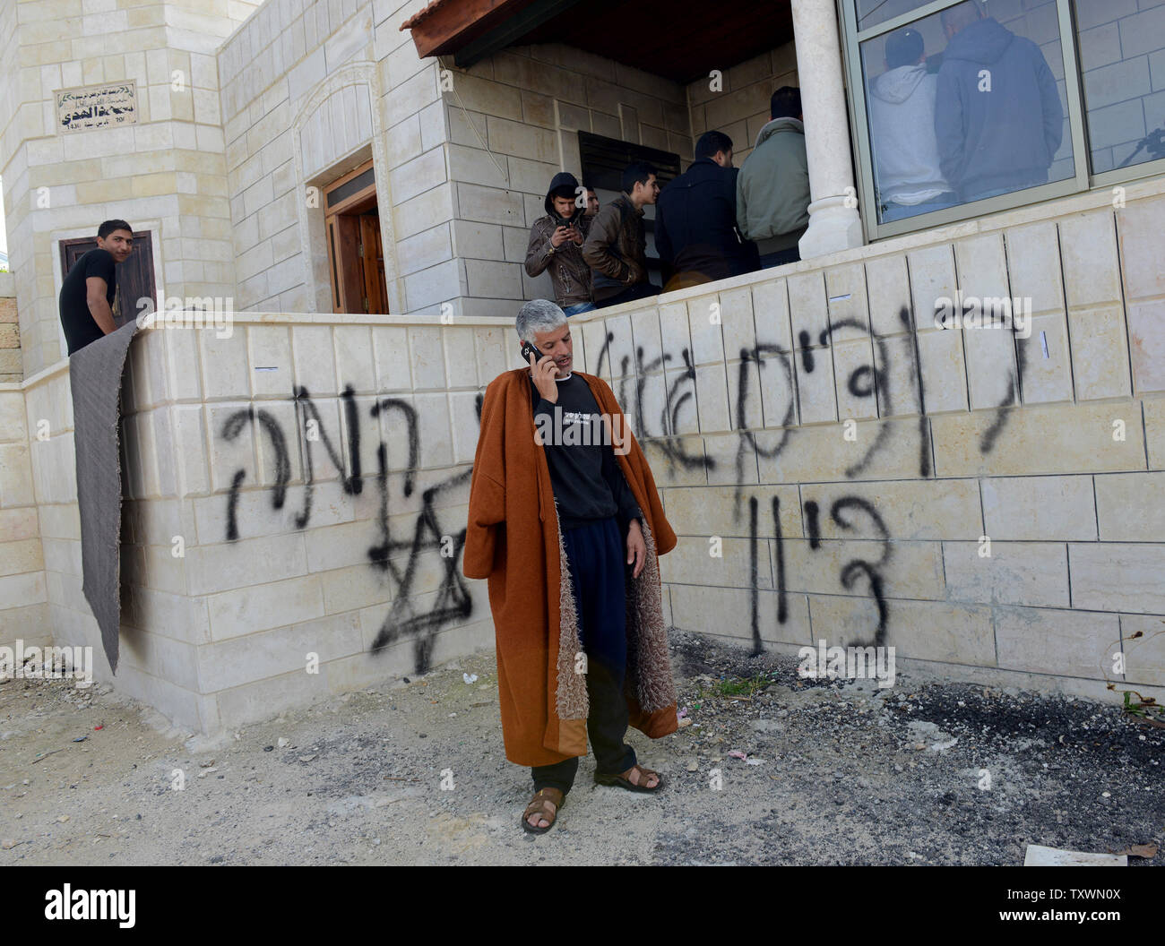 Eine palästinensische steht außerhalb einer Moschee, die in Brand gesteckt wurde und mit Graffiti in einem 'Preis' hassen Angriff von extremistischen Jüdischen Siedler in Al Jaba' ah, in der Nähe von Bethlehem gesprüht, in der West Bank, 25. Februar 2015. Die palästinensischen Bewohner sagen, sie sahen die israelischen Siedler in der Nähe der Moschee, als er frühen Mittwoch Morgen angegriffen. Ein Davidstern und "Rache" und "Wir wollen die Erlösung von Zion' außerhalb der Moschee gemalt wurden. Foto von Debbie Hill/UPI Stockfoto