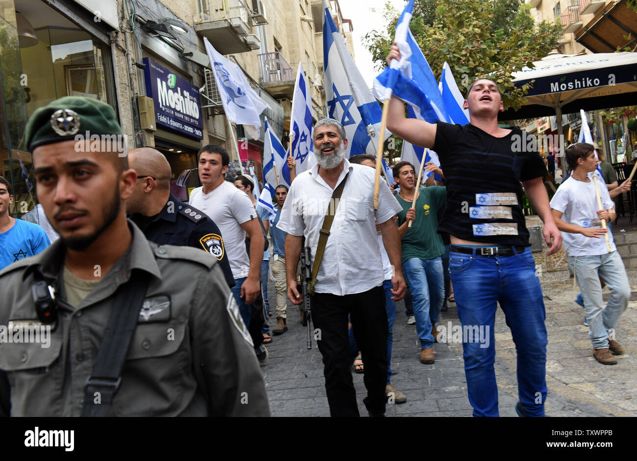 Ein israelischer Siedler führt eine automatische Waffe während marschieren mit Jugend winken die Nationalflagge und Singen ein hebräisches Lied, dass der sagt: "Wer glaubt an Gott keine Angst" während einer Demonstration im Zentrum von Jerusalem, Israel, 18. Oktober 2015. Die Siedler zogen aus Protest gegen eine Welle des Terrors erstechen Angriffe von Palästinensern auf Israelis. Foto von Debbie Hill/UPI Stockfoto