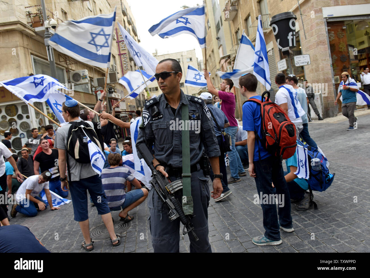 Eine israelische Polizei wachen israelische Siedler Tanz mit der Nationalflagge und Singen ein hebräisches Lied, dass der sagt: "Wer glaubt an Gott keine Angst" während einer Demonstration im Zentrum von Jerusalem, Israel, 18. Oktober 2015. Die Siedler zogen aus Protest gegen eine Welle des Terrors erstechen Angriffe von Palästinensern auf Israelis. Foto von Debbie Hill/UPI Stockfoto