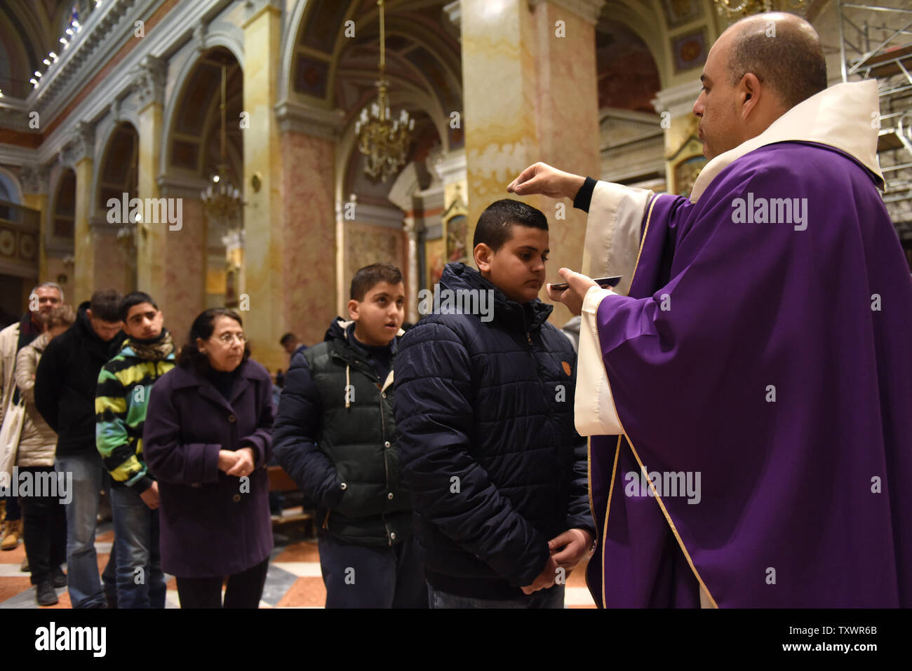 Ein katholischer Priester Orte Asche auf dem Kopf eines Jungen während der Messe am Aschermittwoch in der Kirche des St. Saviour in der Altstadt von Jerusalem, 10. Februar 2016. Aschermittwoch ist der erste Tag der Fastenzeit, in der die heilige Fasten und Gebet beginnt. Es fällt 46 Tage vor Ostersonntag und stammt aus der alten jüdischen Tradition der Buße und des Fastens. Die Asche aus dem palm Niederlassungen von Palm Sonntag Masse des Vorjahres vorgenommen und auf den Kopf oder Stirn den Staub aus dem Gott Menschen zu symbolisieren. Foto von Debbie Hill/UPI Stockfoto