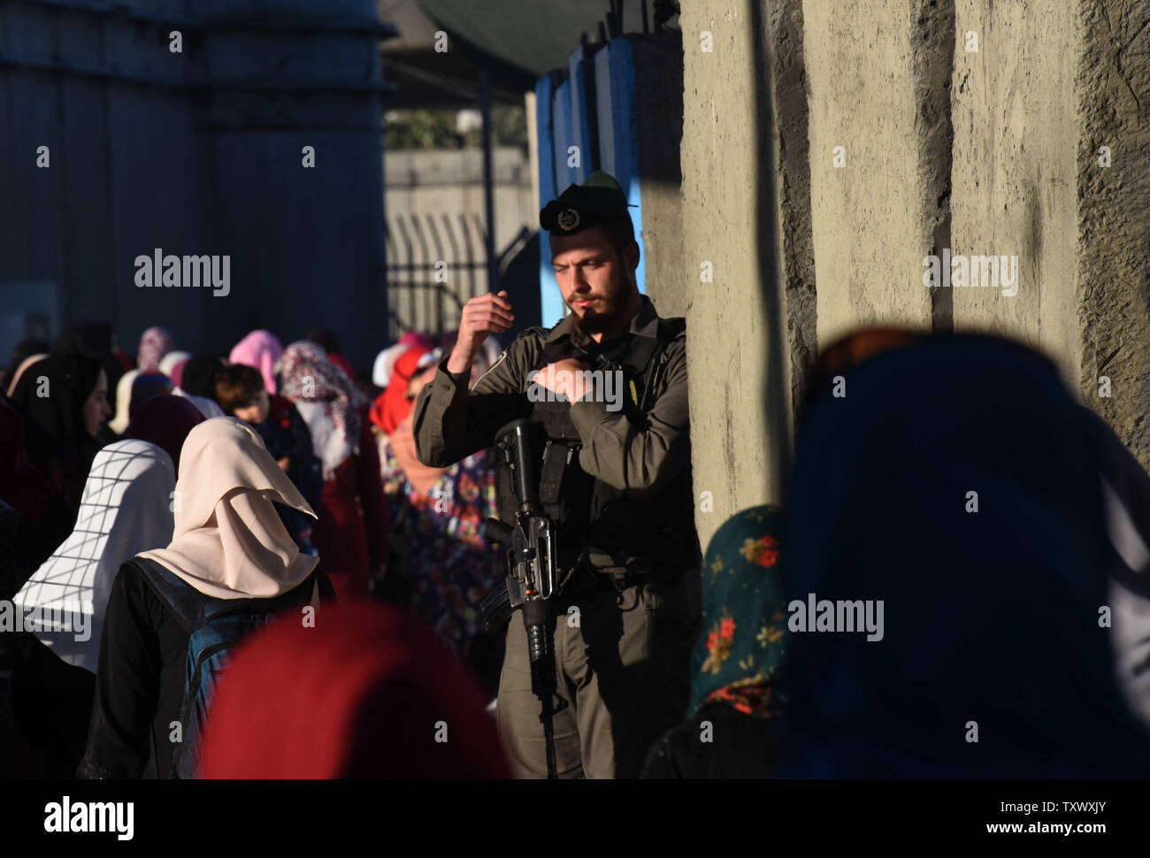 Ein israelischer Soldat leitet Palästinensischen Anbeter, die durch den Checkpoint Qalandiya, West Bank, auf ihre Weise das Freitagsgebet auf dem dritten Freitag des muslimischen Fastenmonats Ramadan an der Al-Aqsa Moschee in der Altstadt von Jerusalem, 16. Juni 2017 teilnehmen. Die qalandiya Checkpoint ist Teil der israelischen Trennungsmauer, Ramallah im Westjordanland von Jerusalem trennt. Foto von Debbie Hill/UPI Stockfoto