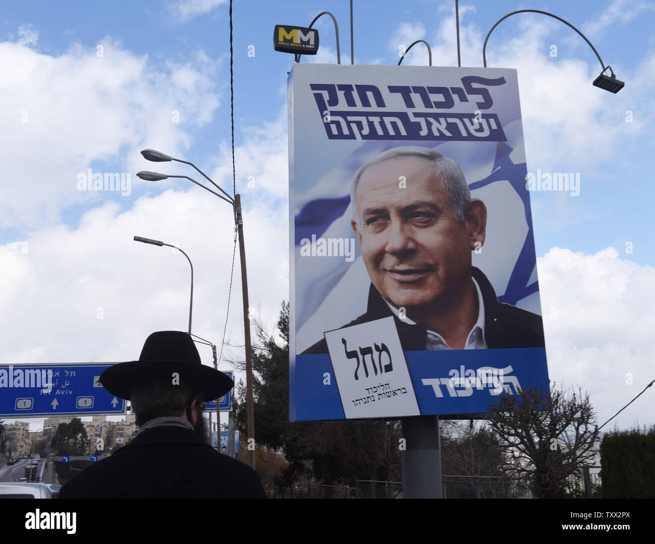 Eine ultra-orthodoxe Mann letzten Wahlkampf Plakat für den israelischen Ministerpräsidenten Benjamin Netanjahu in Jerusalem, 1. April 2019. Über 500 gefälschte social media Konten haben, über den ein Watchdog Gruppe ausgesetzt worden, die Förderung Netanjahus Wiederwahl. Die gefälschte Konten haben 2,5 Millionen Treffer. Israelis Abstimmung am 9. April. Foto von Debbie Hill/UPI Stockfoto