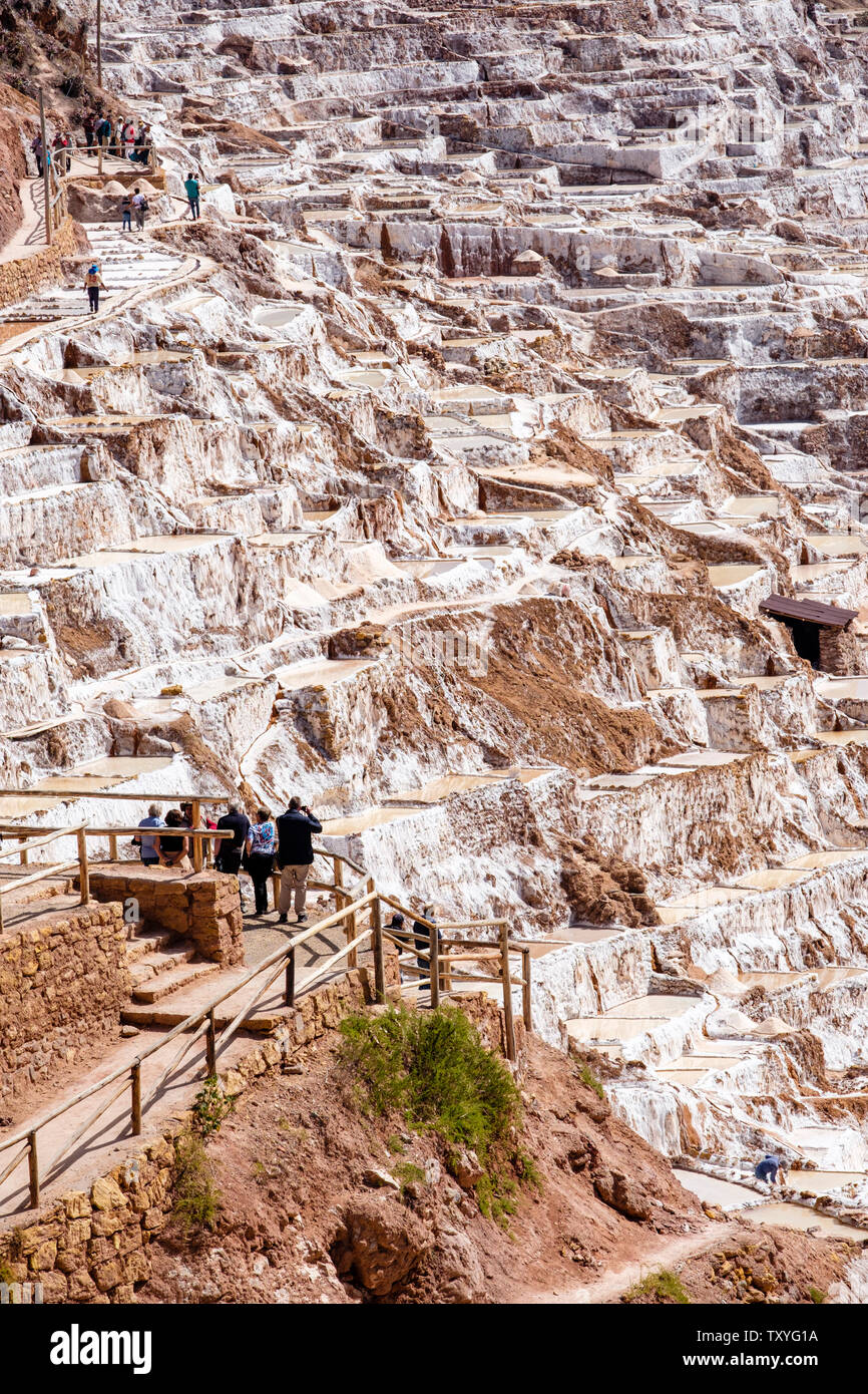 Touristen, die in salineras de Maras/Maras Salzminen. Die Salzgewinnung in Maras Salinen, Terrassen und Teichen, Peru Sacred Valley. Stockfoto