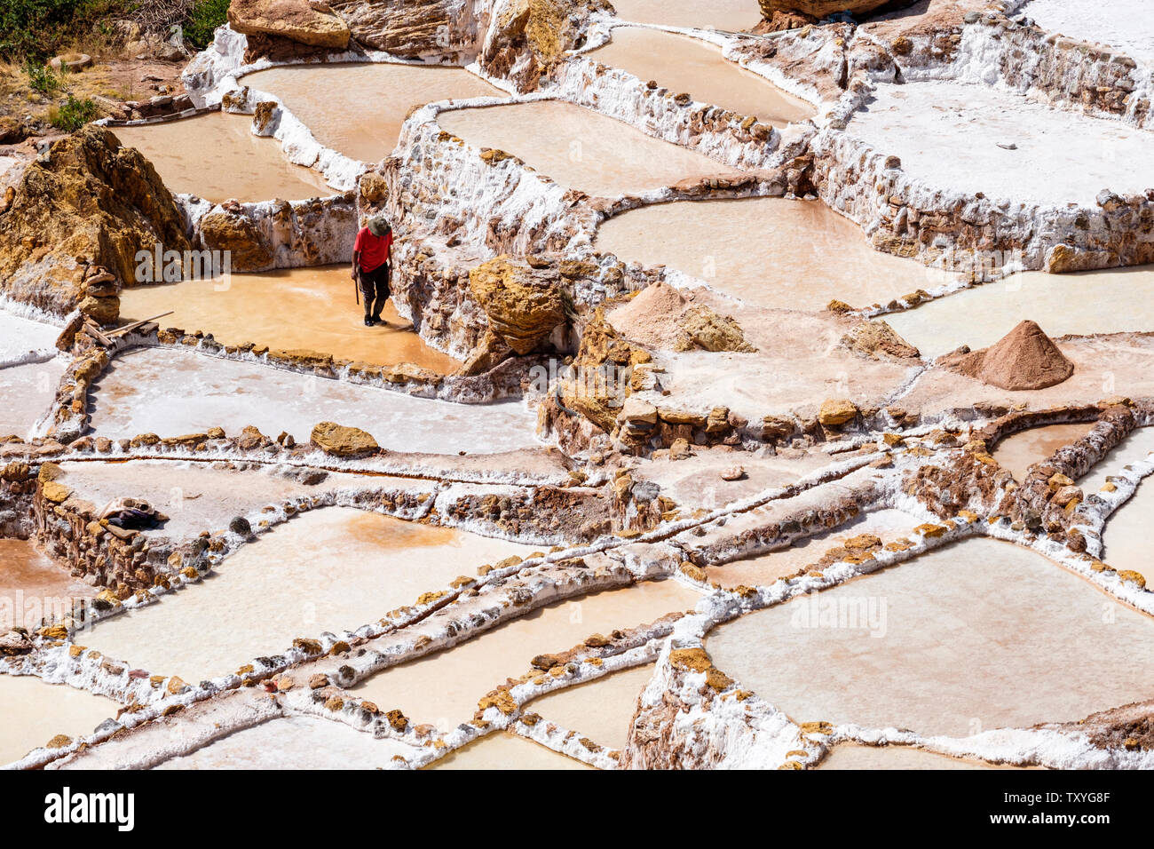 Mann bei der Arbeit auf Salineras de Maras/Maras Salzminen. Die Salzgewinnung in Maras Salinen, Terrassen und Teichen, Peru Sacred Valley. Stockfoto