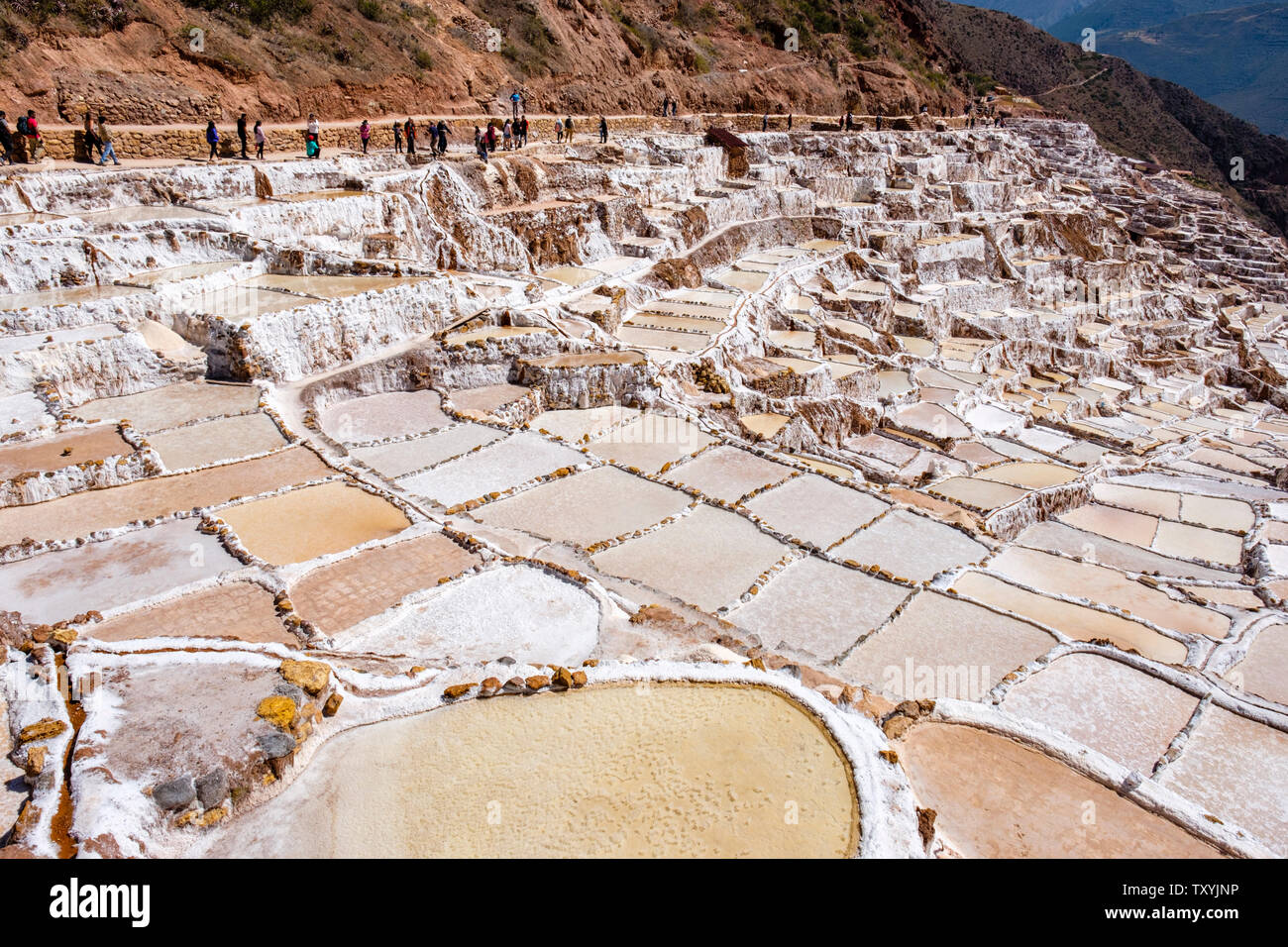 Touristen am salineras de Maras/Maras Salzminen. Die Salzgewinnung in Maras Salinen, Terrassen und Teichen, Peru Sacred Valley. Stockfoto