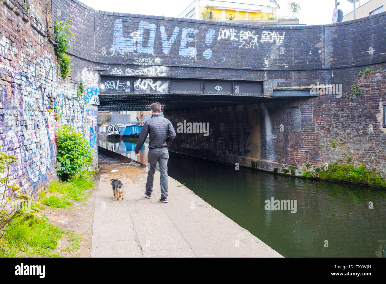 Hackney, East London, England, UK - April 2019: Mann gehen der Hund entlang der Regent's Canal in der Nähe von Broadway, East London Stockfoto