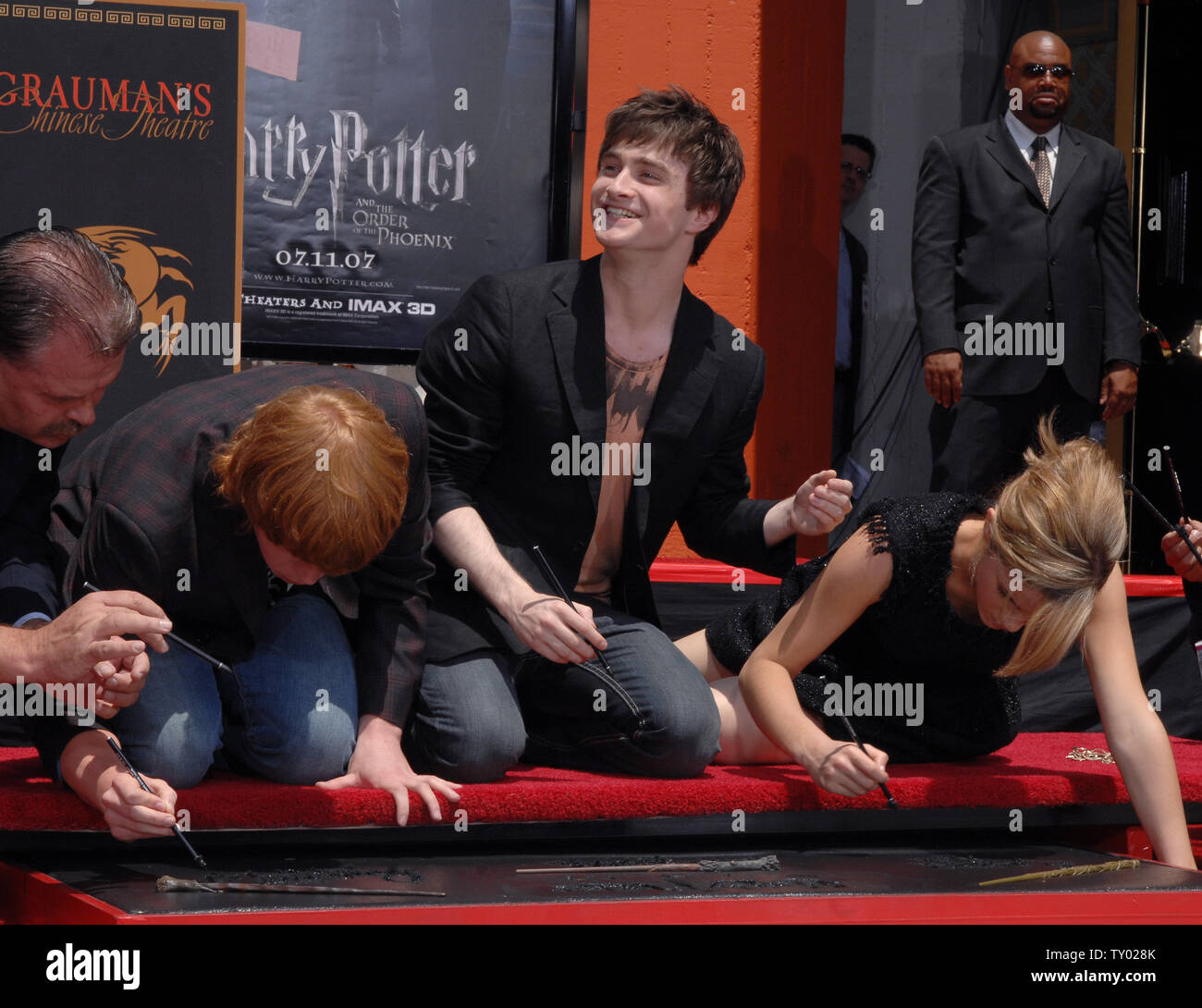 Daniel Radcliffe, die Sterne in The Motion Picture "Harry Potter und der Orden des Phoenix Lächeln in Richtung Fans als seine Co-stars Rupert Grint (L) und Emma Watson ihre Namen in feuchtem Zement schreiben während einer Zeremonie in den Vorplatz der Grauman's Chinese Theater in Hollywood" in Los Angeles am 9. Juli 2007. 'Harry Potter und der Orden des Phönix", dem fünften Film der Reihe, weltweit in dieser Woche veröffentlicht werden. (UPI Foto/Jim Ruymen) Stockfoto