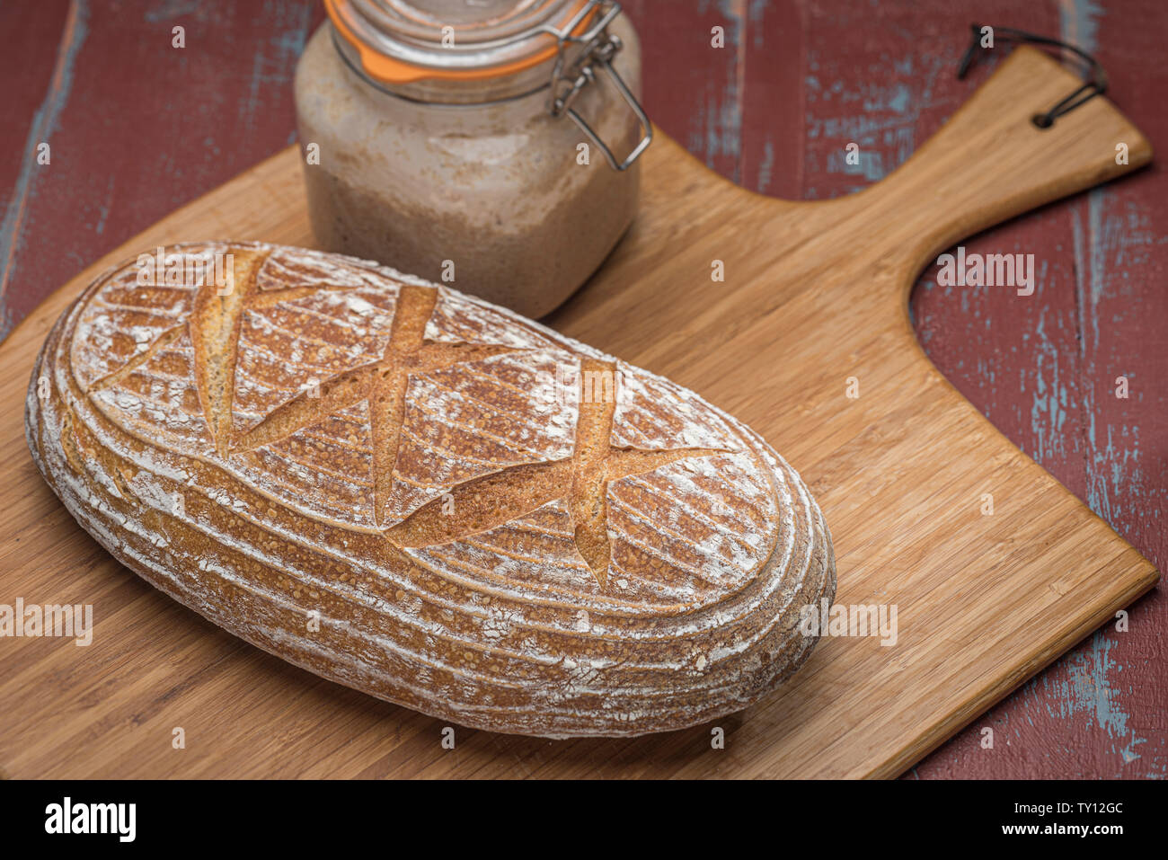 Laib Sauerteigbrot auf Holzbrett mit Kilner jar von fermentierten Starter Kultur. Stockfoto