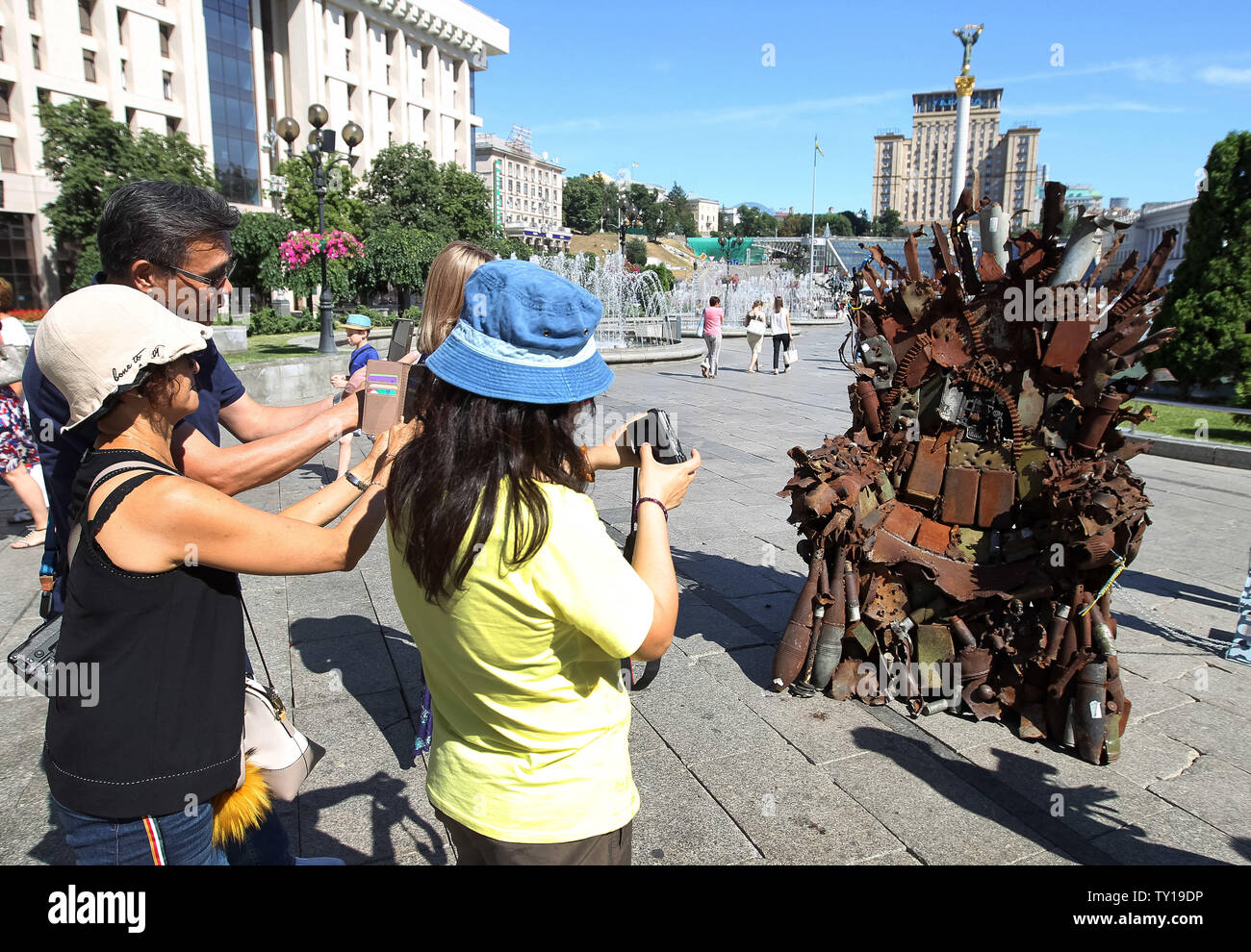 Kiew, Kiew, Ukraine. 25. Juni 2019. Touristen machen Fotos von den Eisernen Thron, während der Präsentation auf dem Platz der Unabhängigkeit in Kiew, Ukraine. Die 600 kg Kunst Arbeiten von Armee freiwillige Denis Bushtets "Eiserne Thron des Ostens'' ist der Tank Stücke, Patrone, Gürtel, Fragmente von Raketen, Maschinengewehre, Granaten, Soldat, Flakons und andere militärische Artefakte, die auf der vorderen Linie mit Russland aufgenommen wurden - unterstützte Separatisten im Osten der Ukraine. Ein Prototyp eines berühmten Bügeleisen Thron von Spiel der Throne TV-Serie ist eine Erinnerung an einen blutigen Konflikt, der bereits rund 13.000 pe getötet hat. Stockfoto