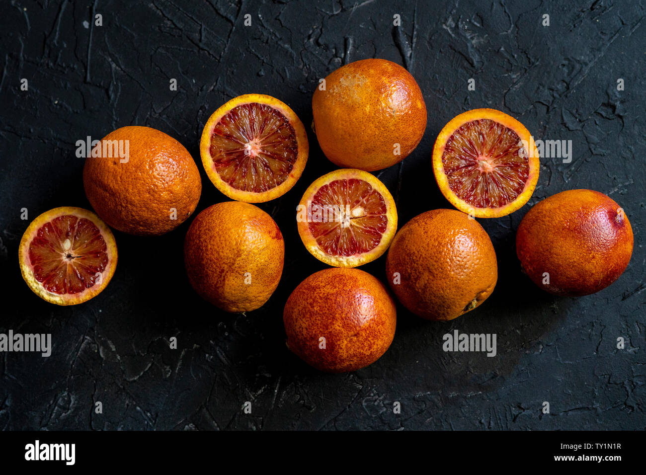 Flach rot geschnitten exotische Orangen, dunklen Essen auf schwarze Flächen Stockfoto