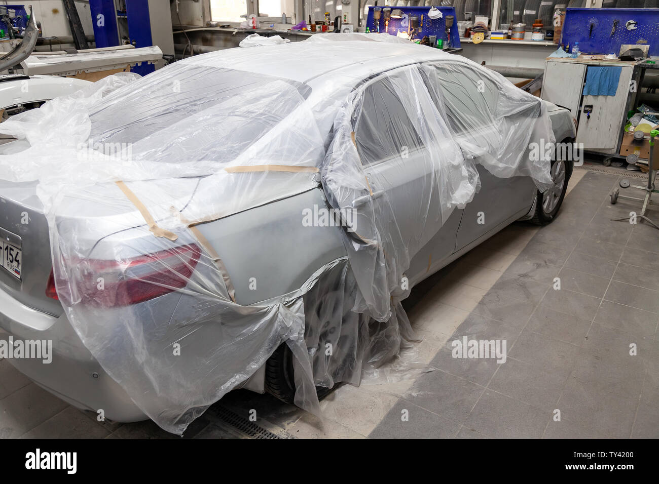Ein kaputtes Auto bedeckt mit einer Schutzfolie von Spritzer Farbe in einer  Lackierkabine in einem Auto Body Repair Shop bevor es gemalt ist und  repariert. Auto se Stockfotografie - Alamy
