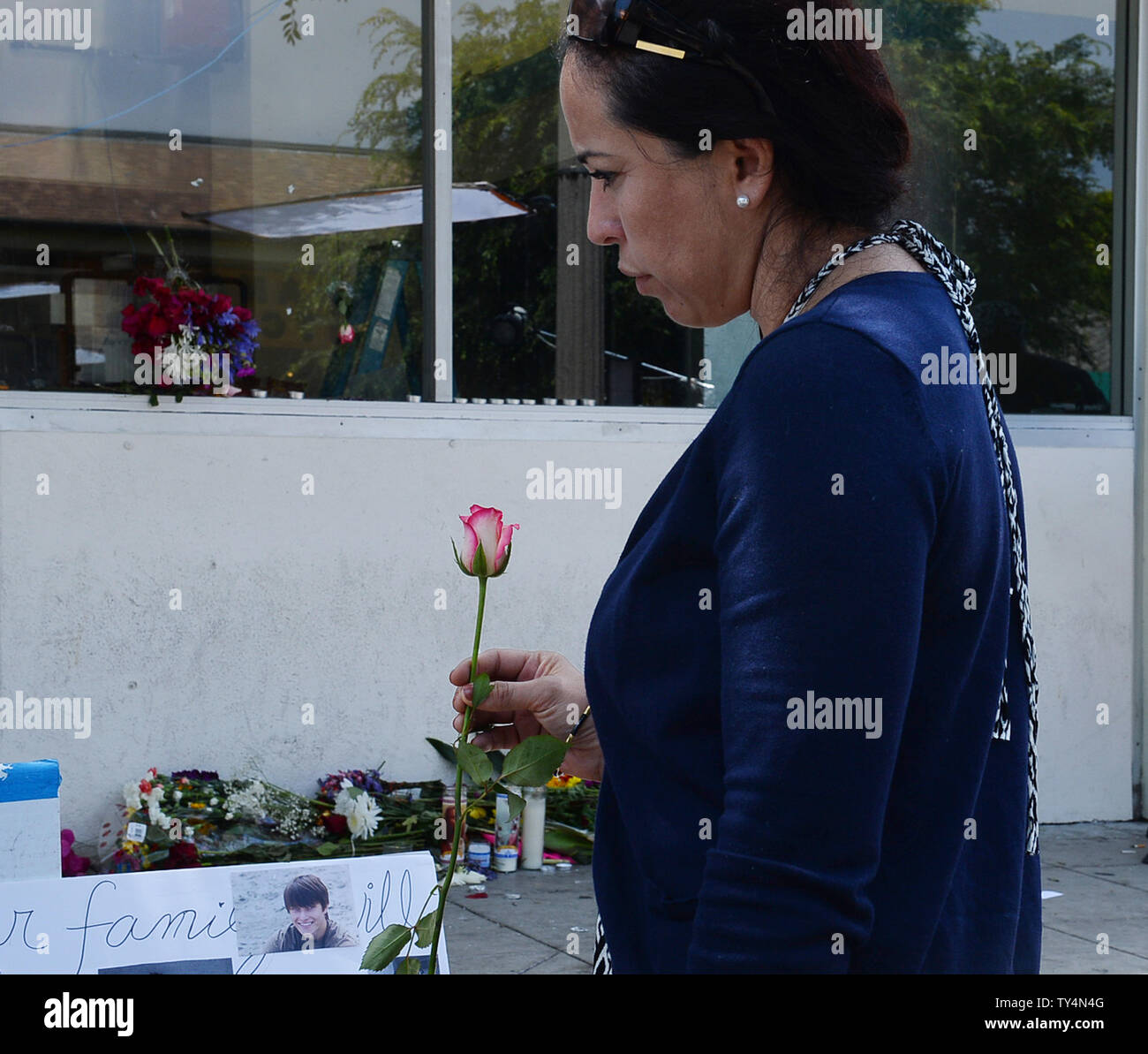 Eine Frau hält eine Blume außerhalb der I.V. Deli Mart in Isla Vista, Kalifornien am 26. Mai 2014, wo Christoph Michaels-Martinez hinunter Freitag Nacht geschossen wurde, eine der Szenen von Elliot O.'s Rodger Rampage. UPI/Jim Ruymen Stockfoto
