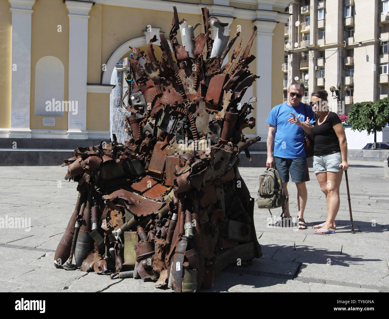 Ein paar Blicke auf den Eisernen Thron, während der Präsentation auf dem Platz der Unabhängigkeit in Kiew, Ukraine. Die 600 kg Kunst Arbeiten von Armee freiwillige Denis Bushtets berechtigt "Eiserne Thron des Ostens' ist der Tank Stücke, Patrone, Gürtel, Fragmente von Raketen, Maschinengewehre, Granaten, Soldat, Flakons und andere militärische Artefakte, die auf der vorderen Linie mit Russland aufgenommen wurden - unterstützte Separatisten im Osten der Ukraine. Ein Prototyp eines berühmten Bügeleisen Thron von Spiel der Throne TV-Serie ist eine Erinnerung an einen blutigen Konflikt, der bereits seit 2014 etwa 13.000 Menschen getötet hat. Stockfoto