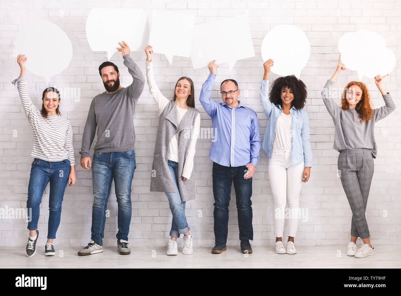 Global Communications. Gruppe der glückliche junge Menschen mit leeren Sprechblasen und Suchen an der Kamera, während gegen grauen Hintergrund stehend Stockfoto Global Communications. Gruppe der glückliche junge Menschen mit leeren Sprechblasen und Suchen an der Kamera, während gegen grauen Hintergrund stehend Stockfoto