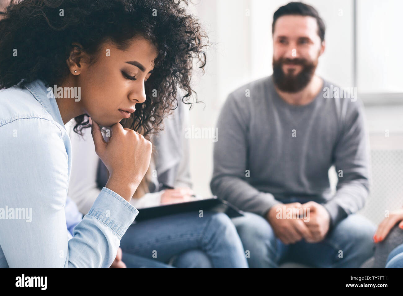 Deprimiert afrikanische Frau sitzen unter fröhliche Menschen zu Therapie Sitzung Stockfoto