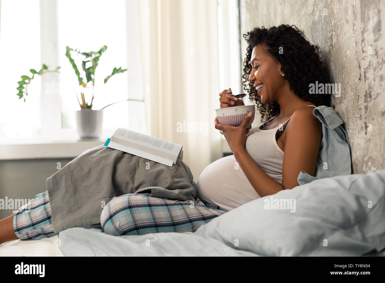 Lächelnd schwangere Frau Frühstück im Bett. Stockfoto