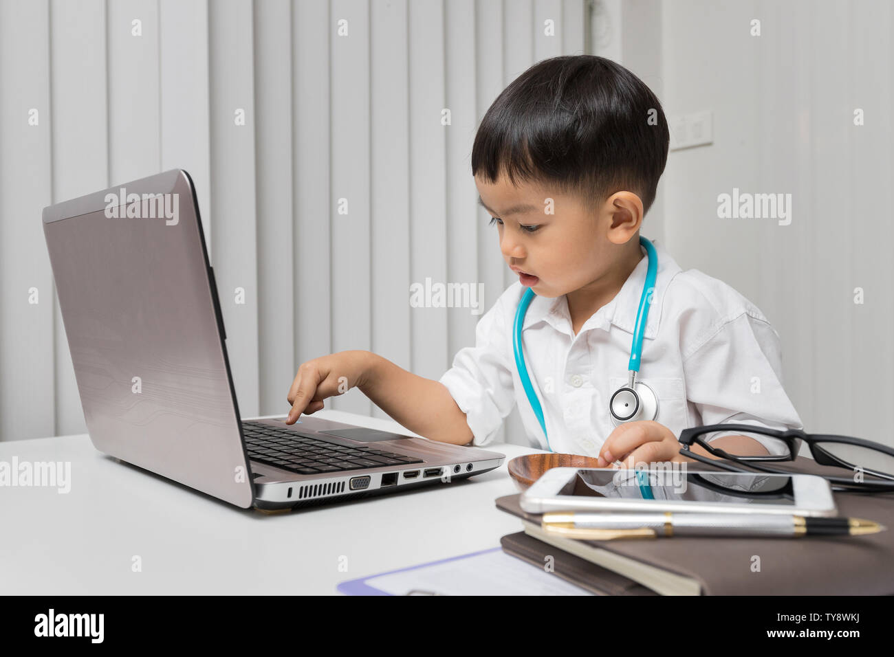 Little Boy In medic Uniform mit einem Laptop auf dem Schreibtisch Stockfoto
