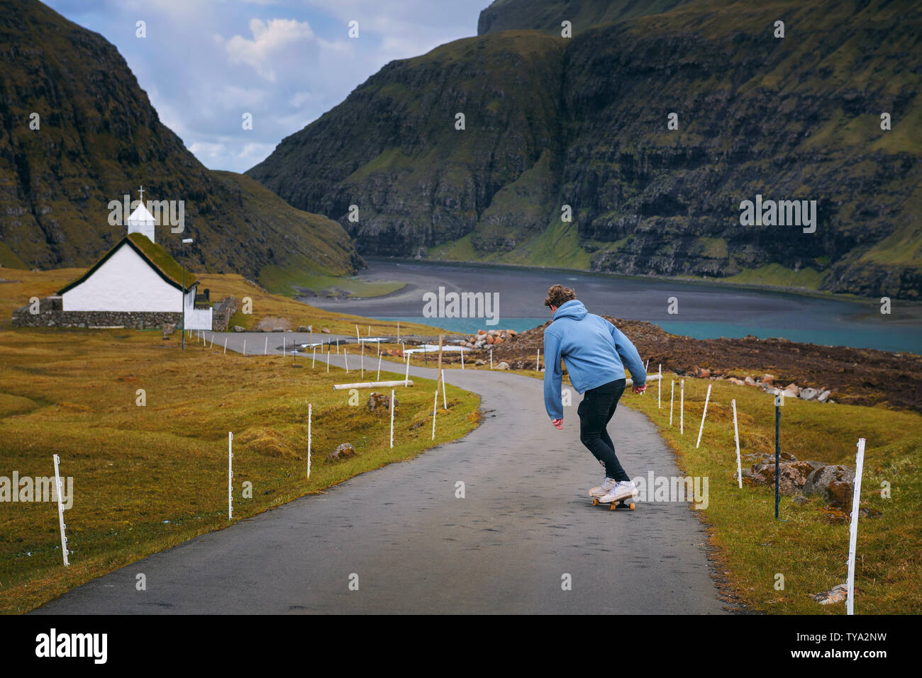Jungen Skater, der auf einem Skateboard durch die wunderschöne Landschaft der Färöer Inseln Stockfoto