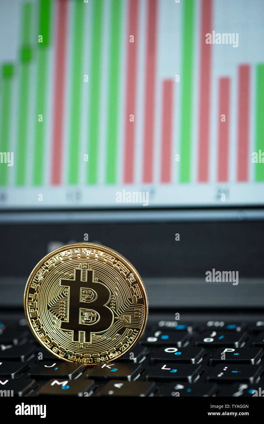 Golden bitcoin auf Laptop Tastatur mit Grafik im Hintergrund Stockfoto