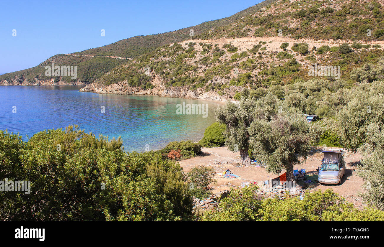 Camping Auto mit hebbarem Dach und wäscheleinen zwischen Olivenbäumen, in der Nähe des Ozeans mit türkisfarbenem Wasser in der Nähe von Pilion, Griechenland. Stockfoto
