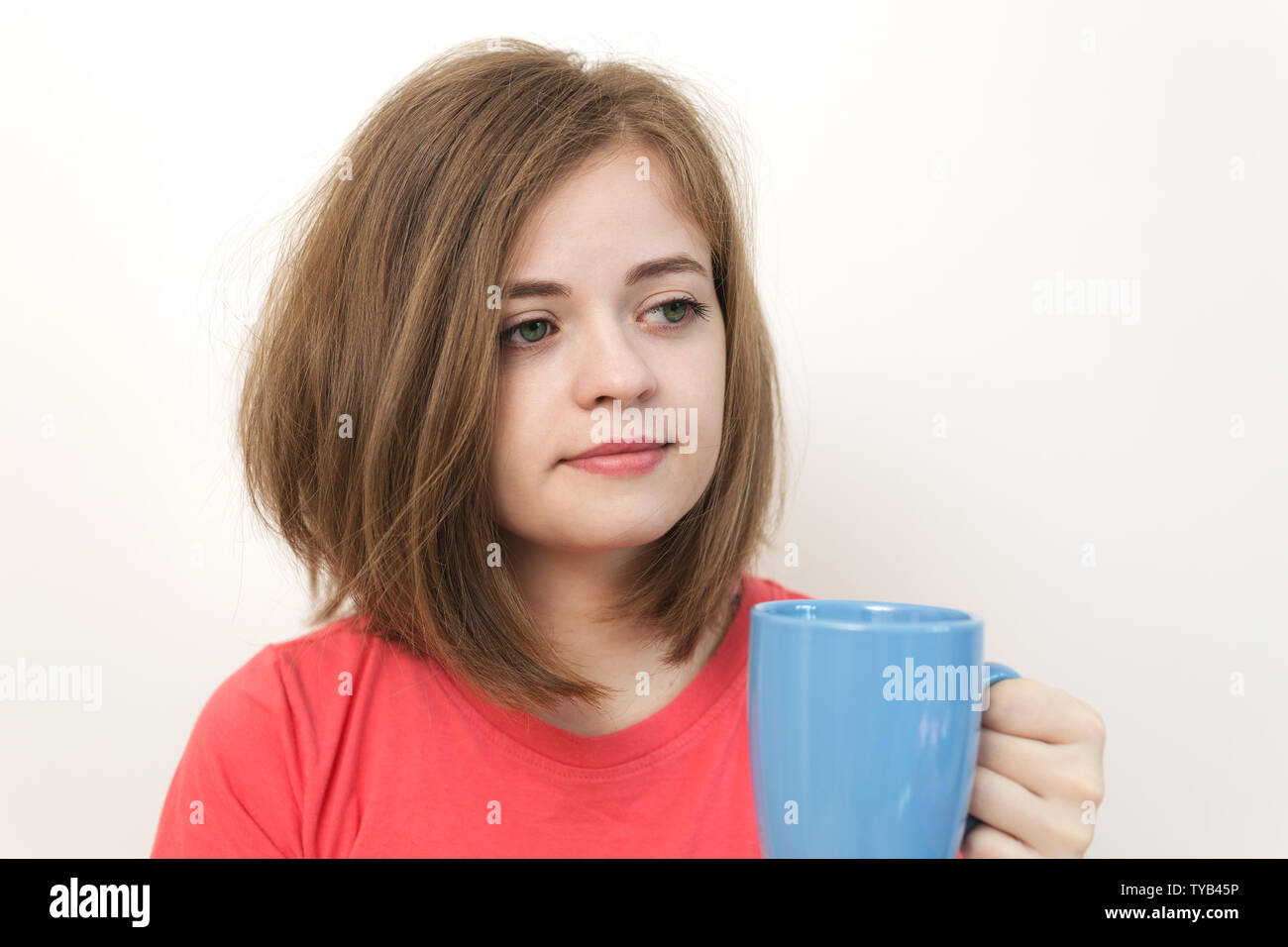 Porträt der jungen kaukasischen Frau Mädchen, Gähnen, müde oder schläfrig mit Buschigem zerzaustes Haar mit einem Becher Kaffee Stockfoto