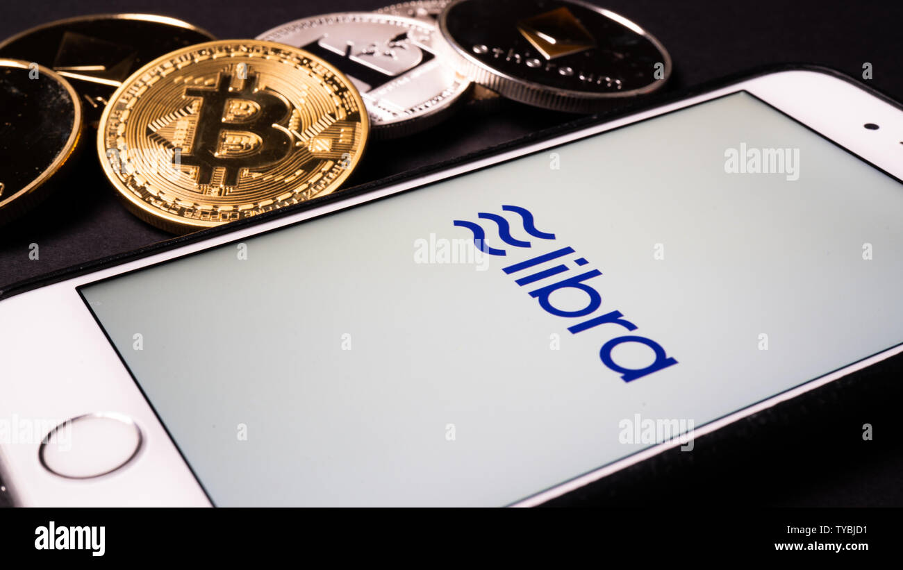 26. Juni 2019, Wuhan China: Waage die Facebook cryptocurrency Logo auf Handy und echten Münzen von anderen Crypto wie Bitcoin daneben Stockfoto