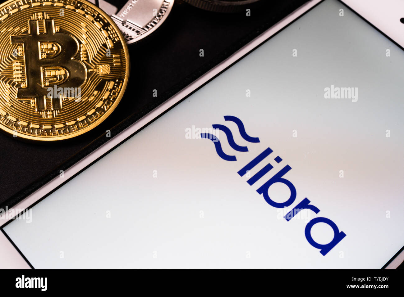 26. Juni 2019, Wuhan China: Waage die Facebook cryptocurrency Logo auf Handy und echten Münzen von anderen Crypto wie Bitcoin daneben Stockfoto