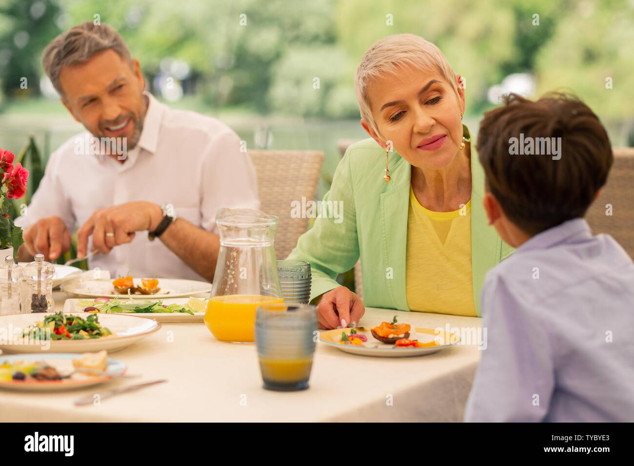 Großmutter kümmert sich um ihren Enkel beim Frühstück Stockfoto